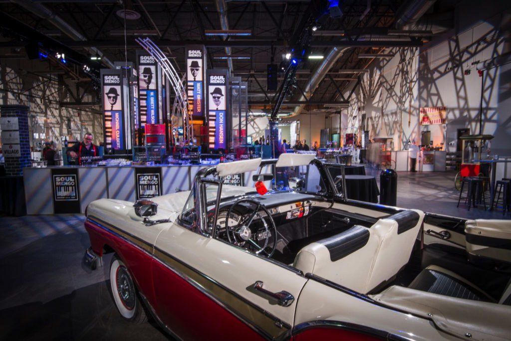 A red and white convertible car is parked in a warehouse.