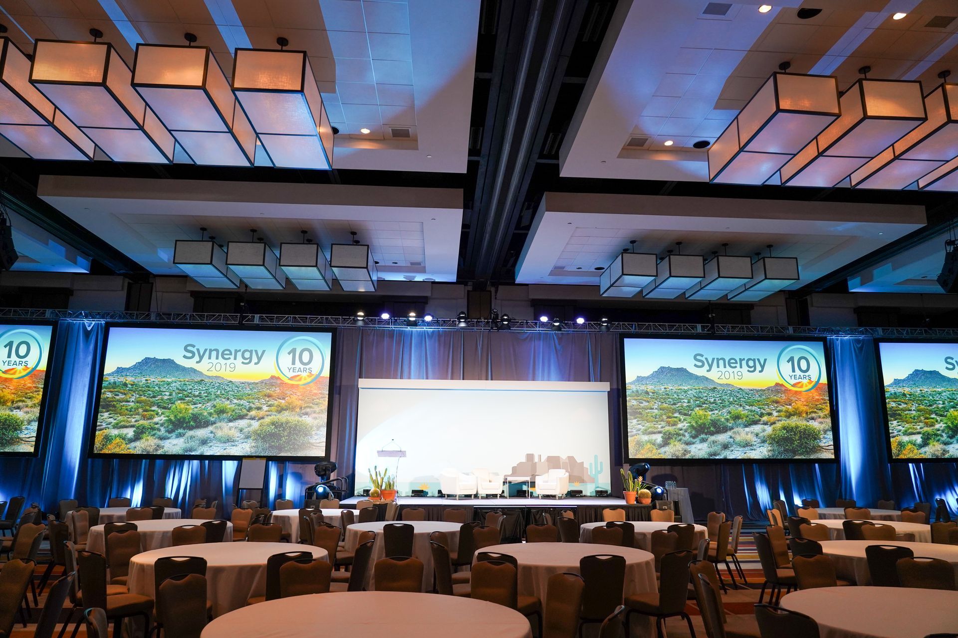 A large conference room with tables and chairs and projector screens