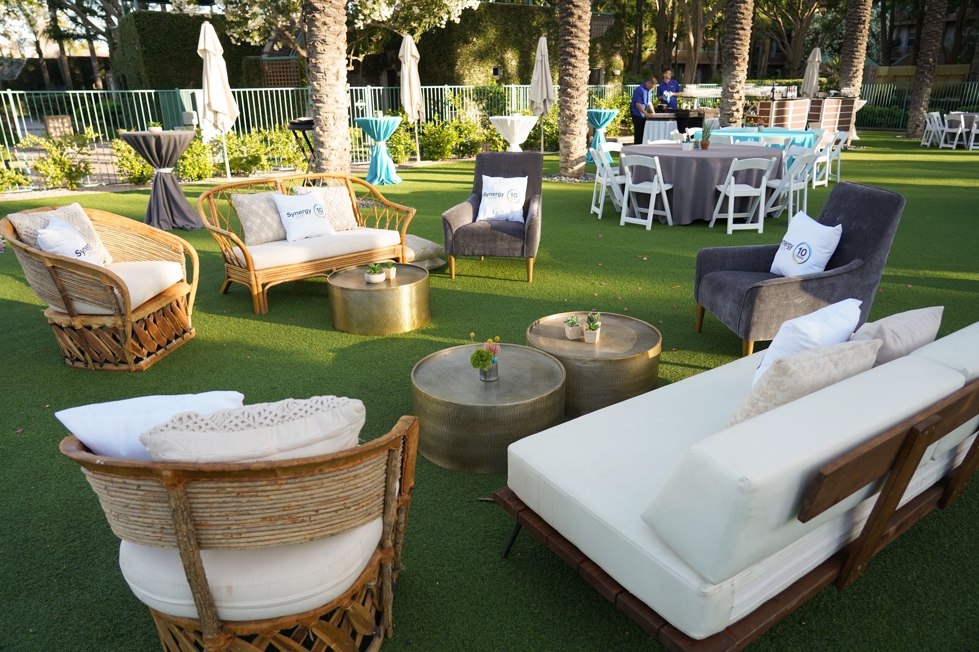 A lawn with a couch , chairs , tables and umbrellas