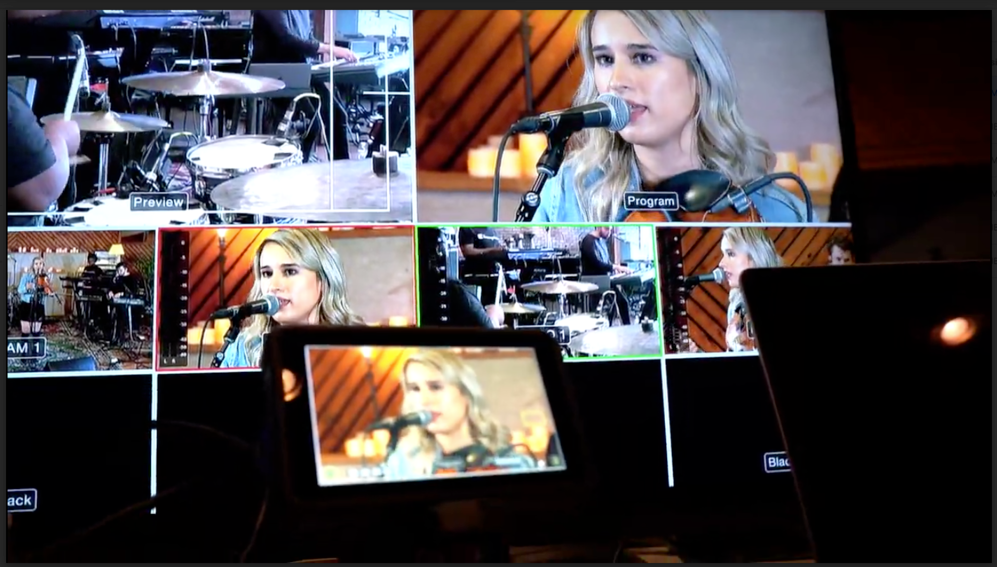 A woman singing into a microphone in front of a drum set