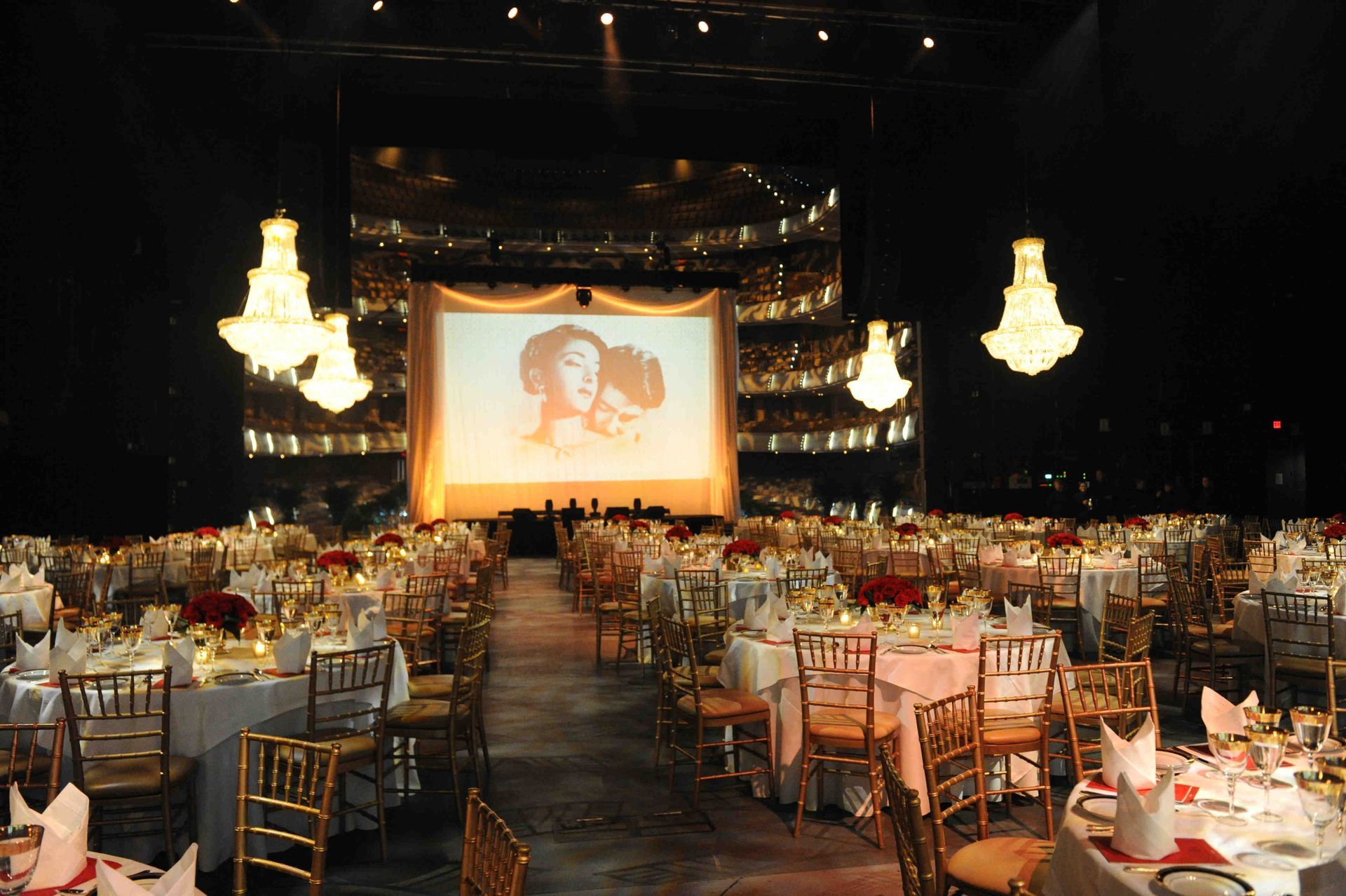 A large room with tables and chairs and a large screen with a picture of leia on it