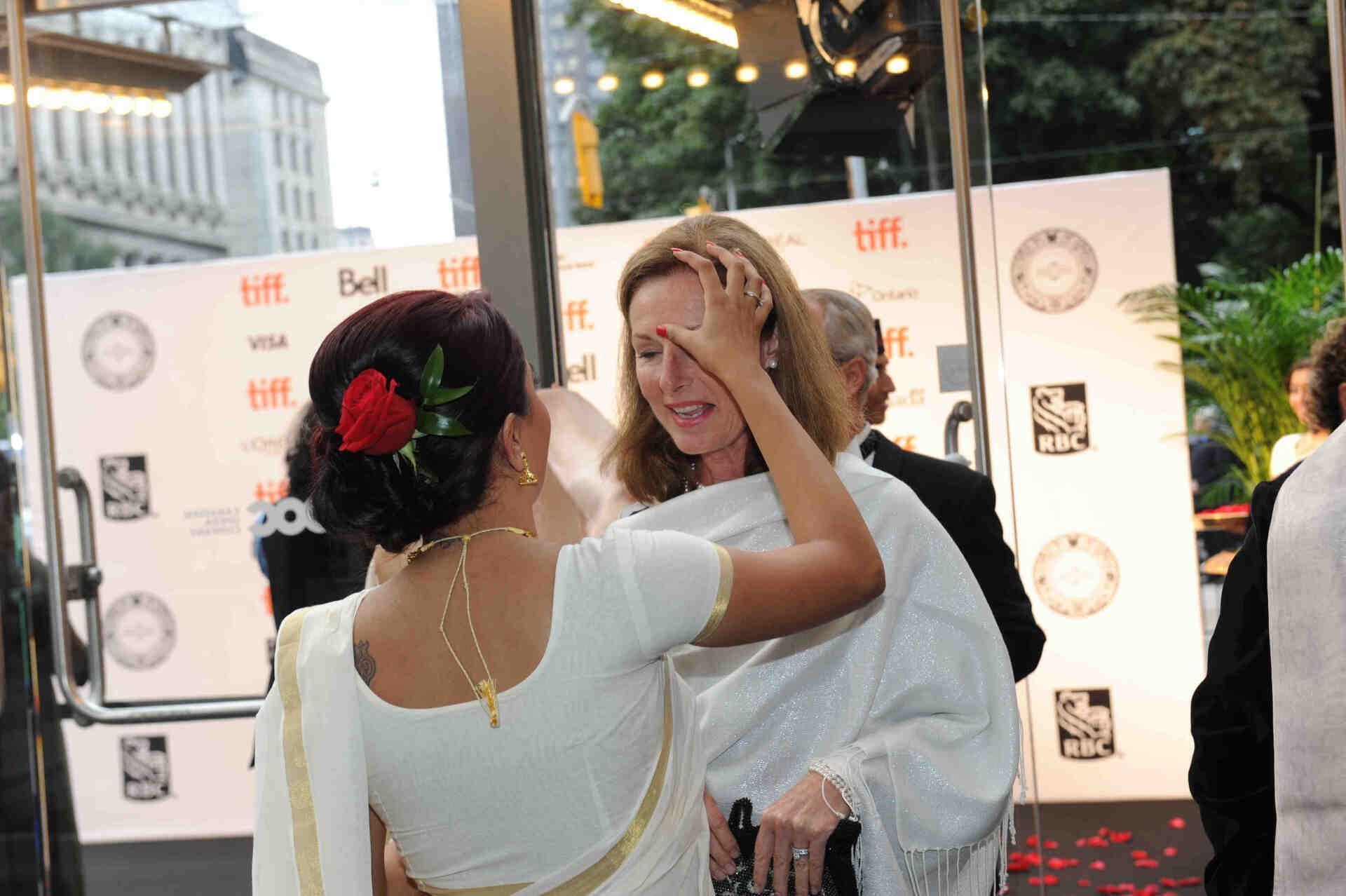 Two women are hugging in front of a sign that says tiff