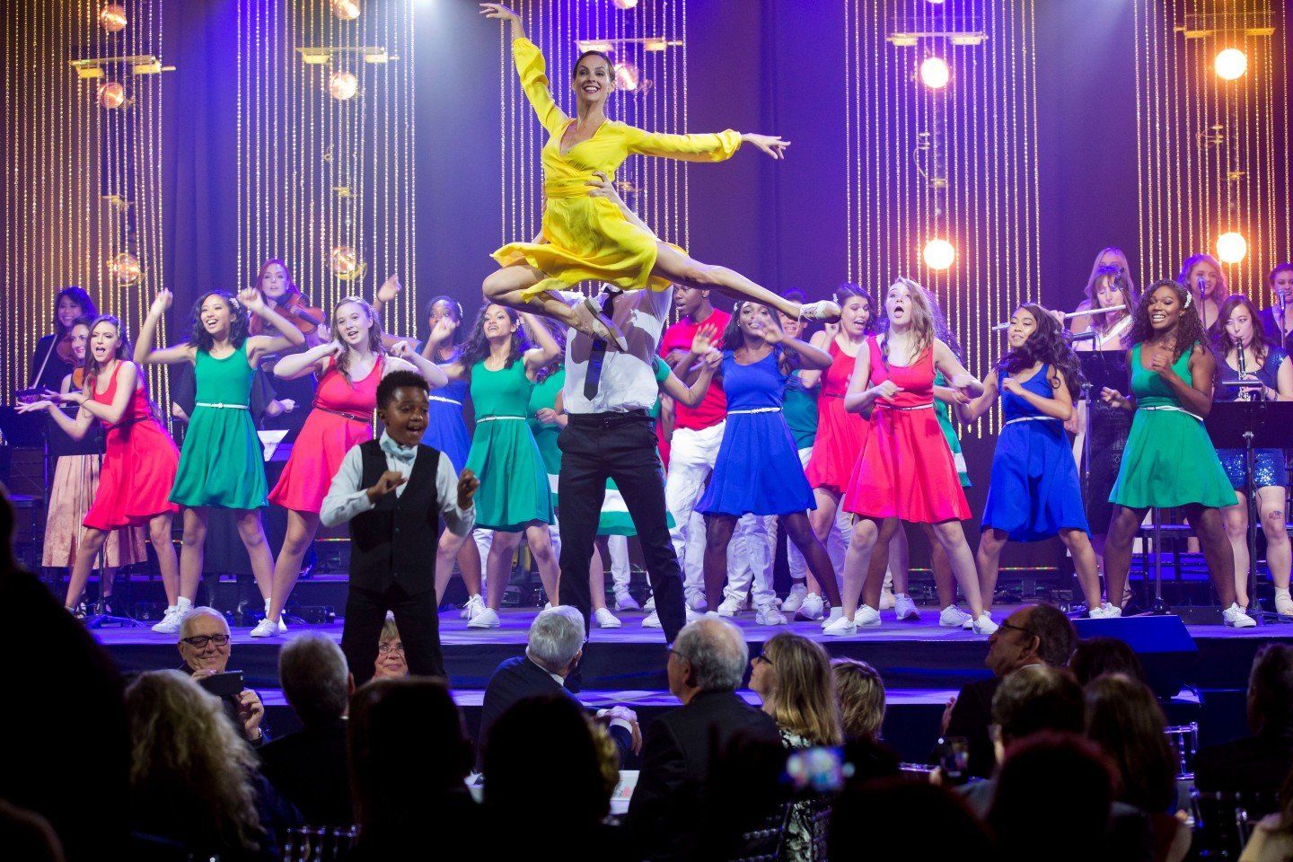 A group of people are dancing on a stage in front of a crowd.