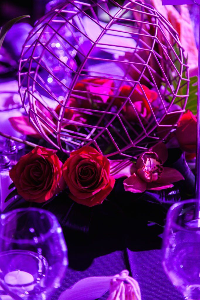 A cage filled with red roses sits on a table.