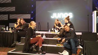 A group of people are sitting on a stage in front of a large screen.