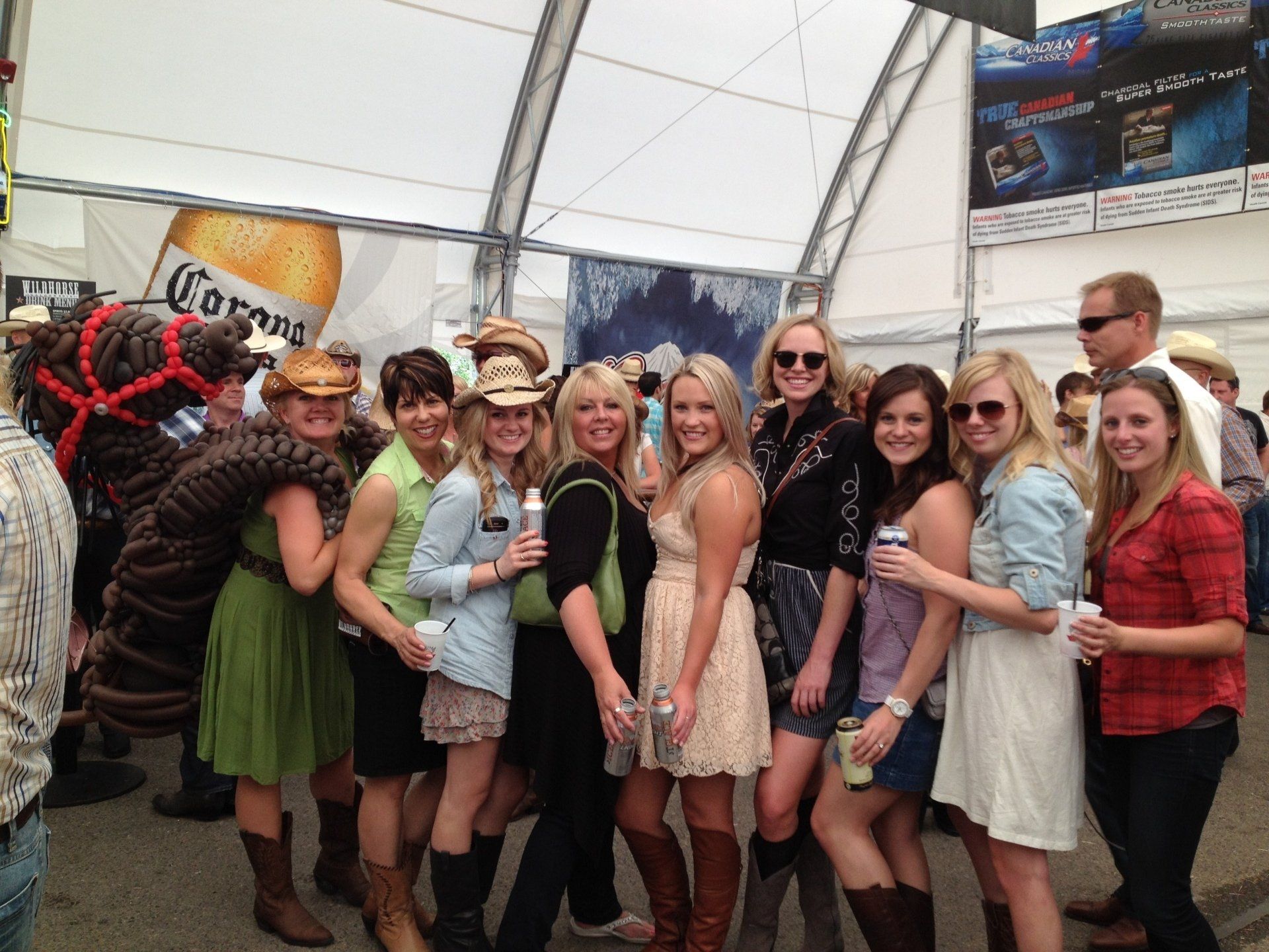 A group of women are posing for a picture in front of a corona beer advertisement