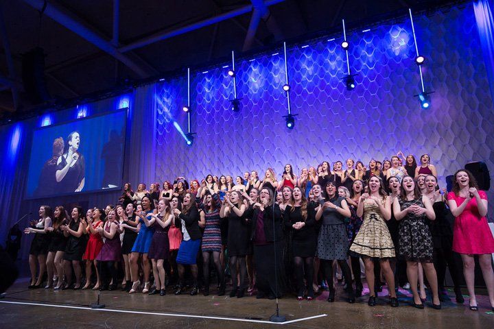 A large group of people are standing on a stage in front of a large screen.