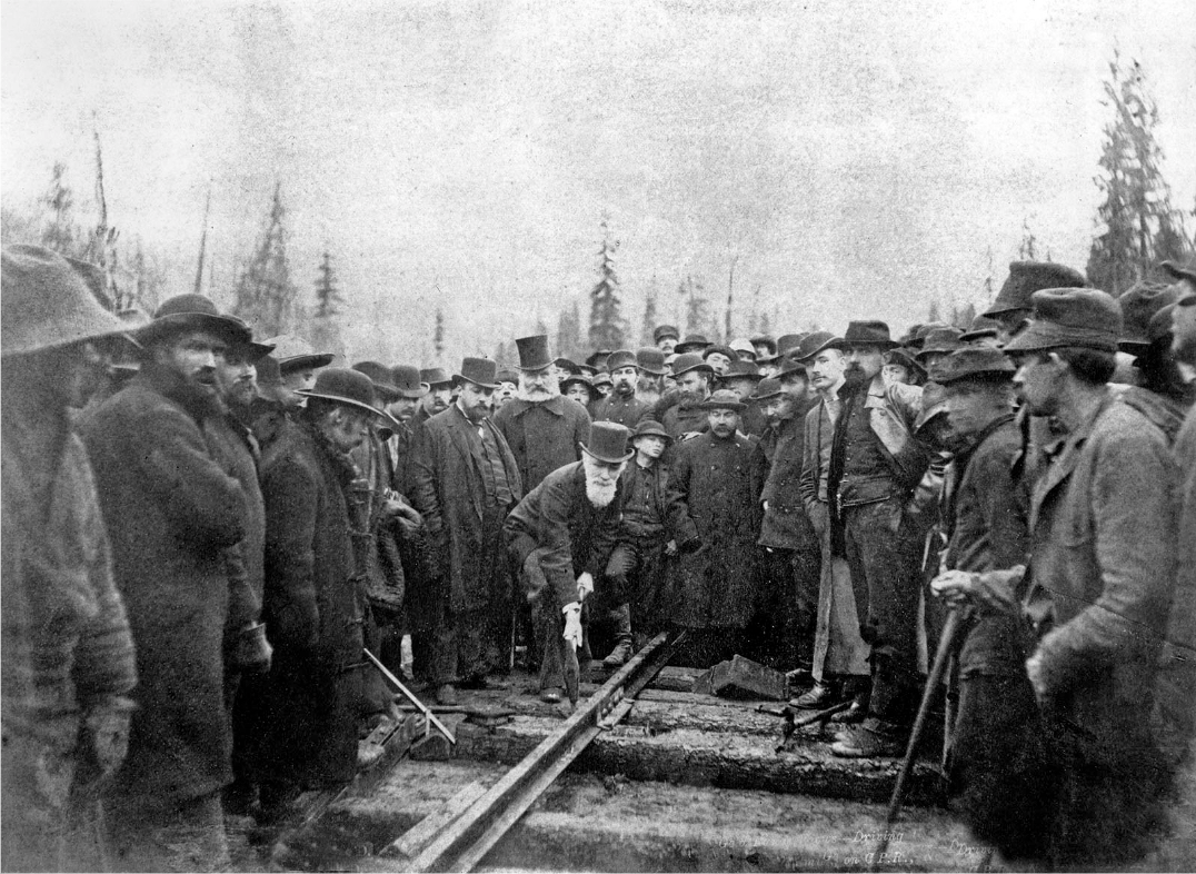 A group of men are standing on train tracks in a black and white photo.
