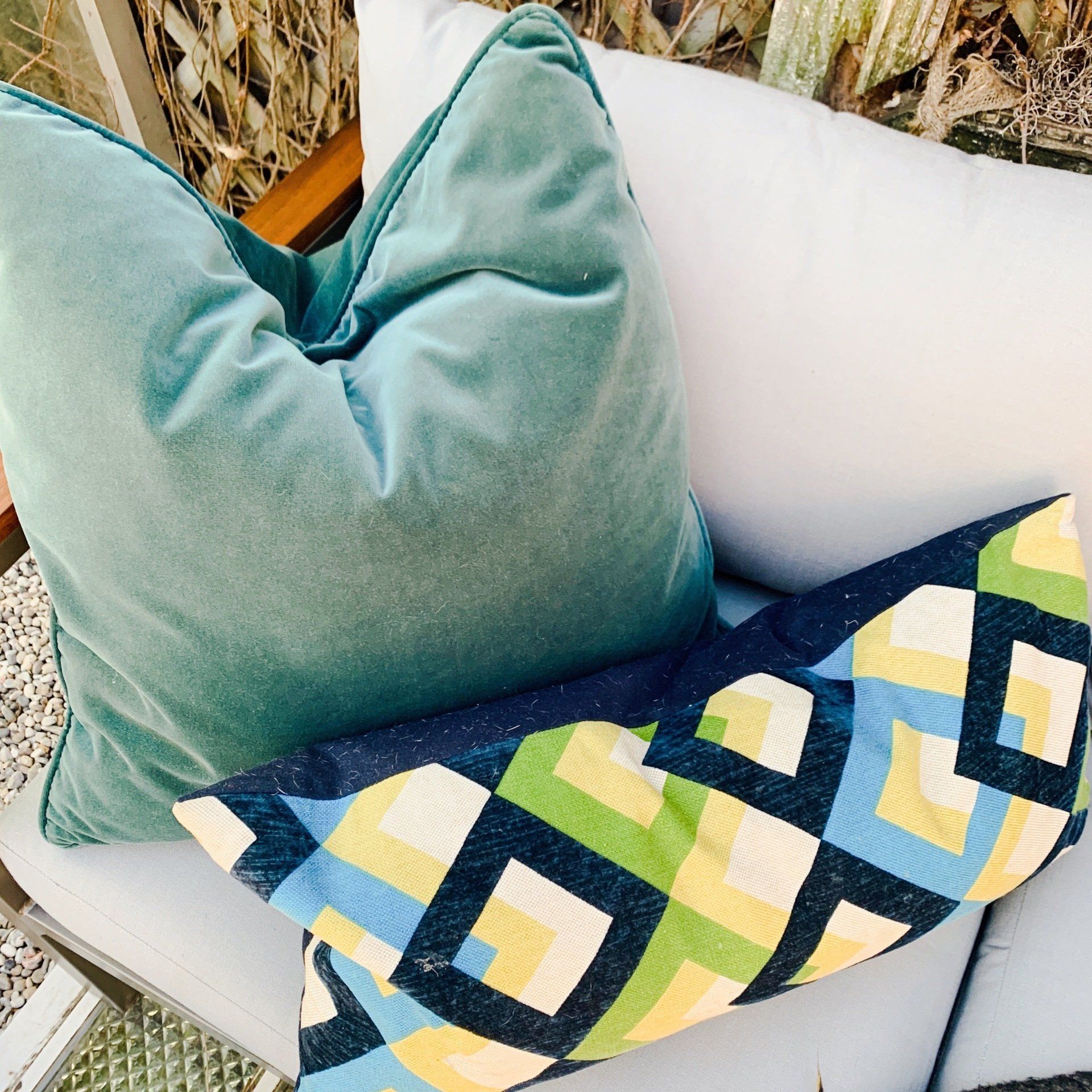 A blue pillow sits on a white couch next to a colorful pillow