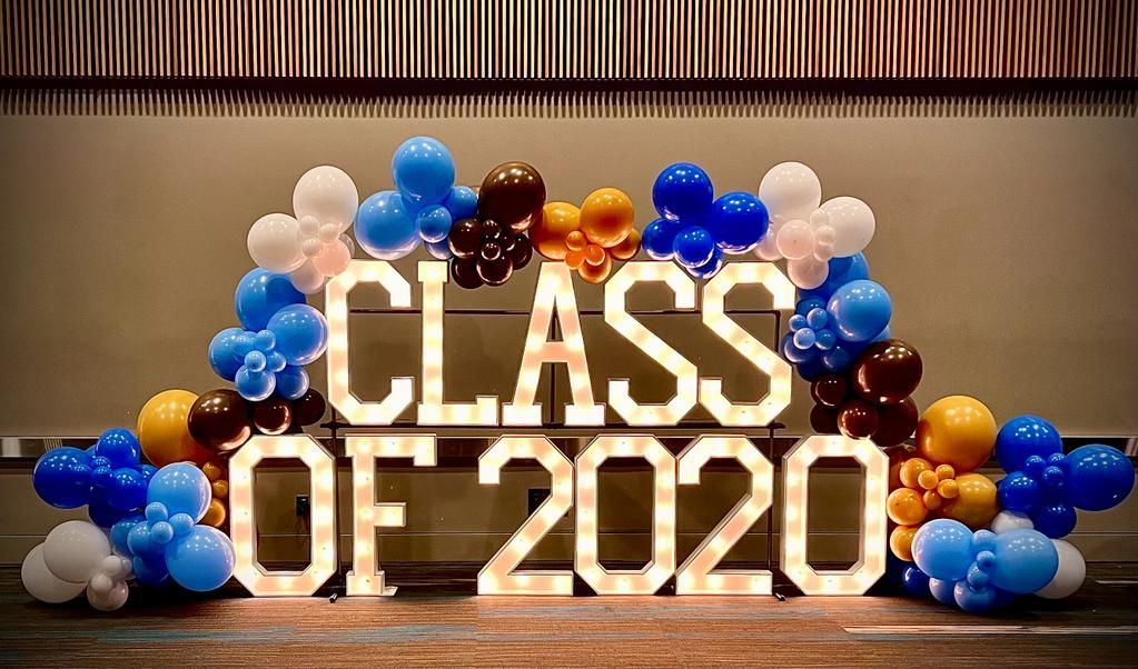 A large sign that says `` class of 2020 '' is surrounded by balloons.