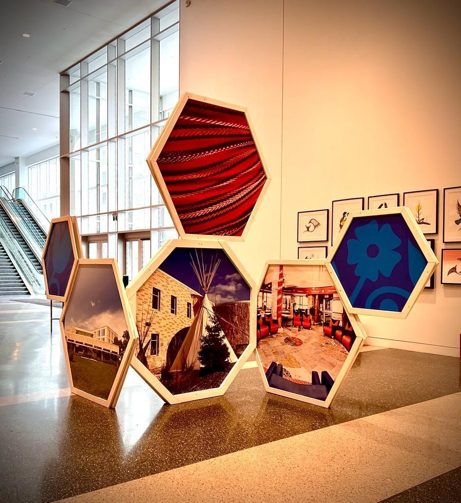 A room with a lot of pictures on the wall and a staircase in the background