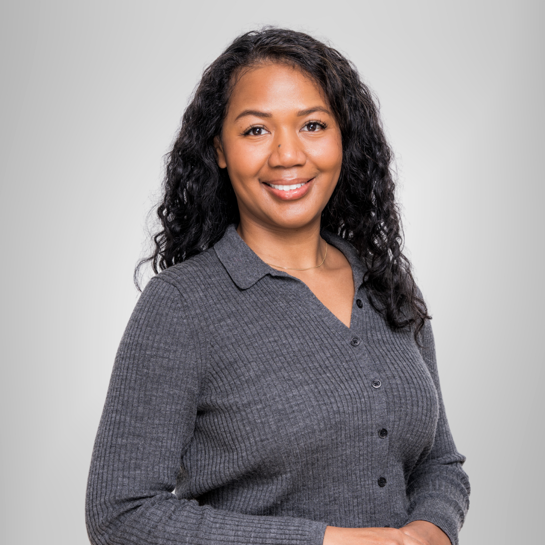 A woman in a grey shirt is smiling for the camera.