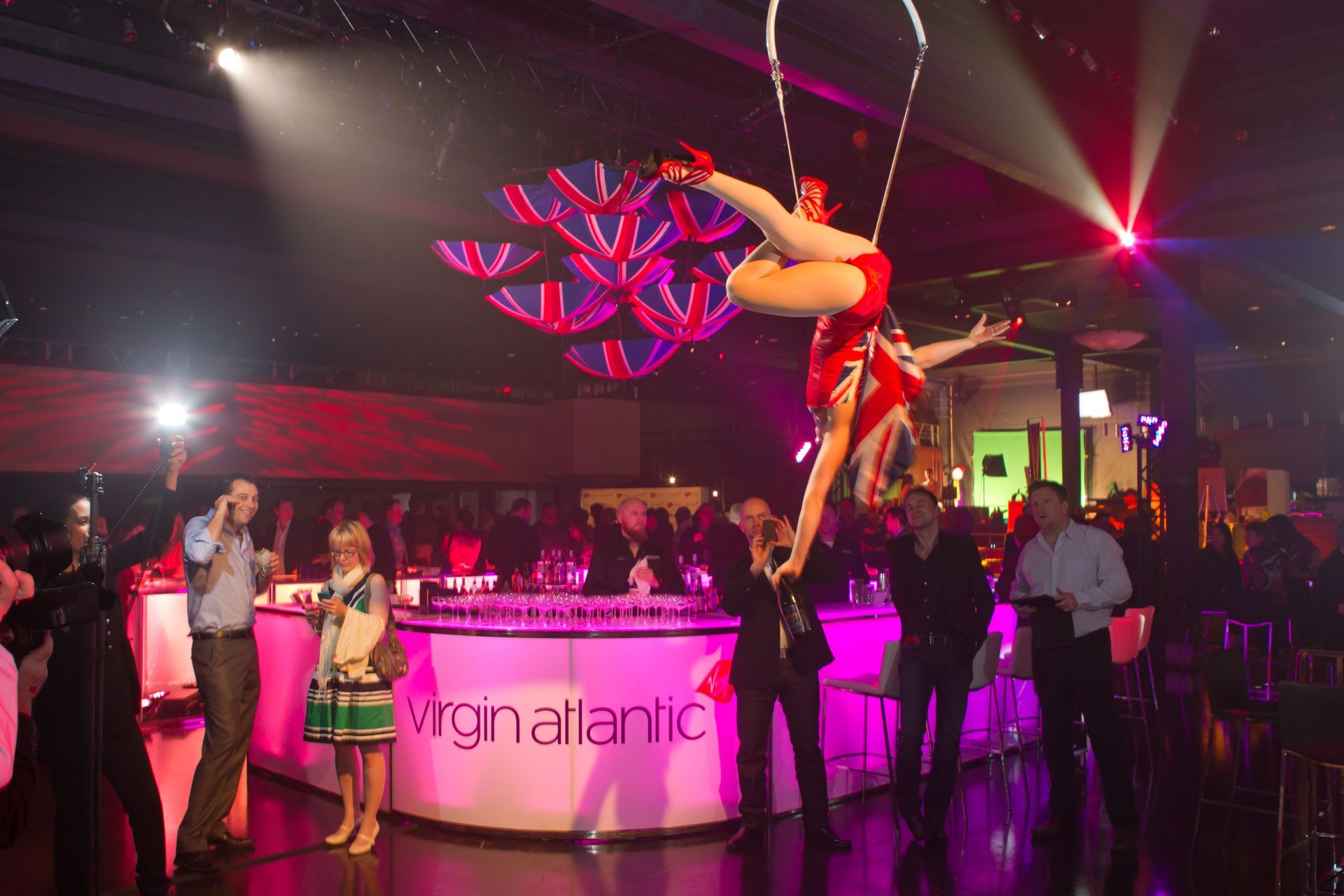 A woman is performing aerial acrobatics in front of a virgin atlantic bar