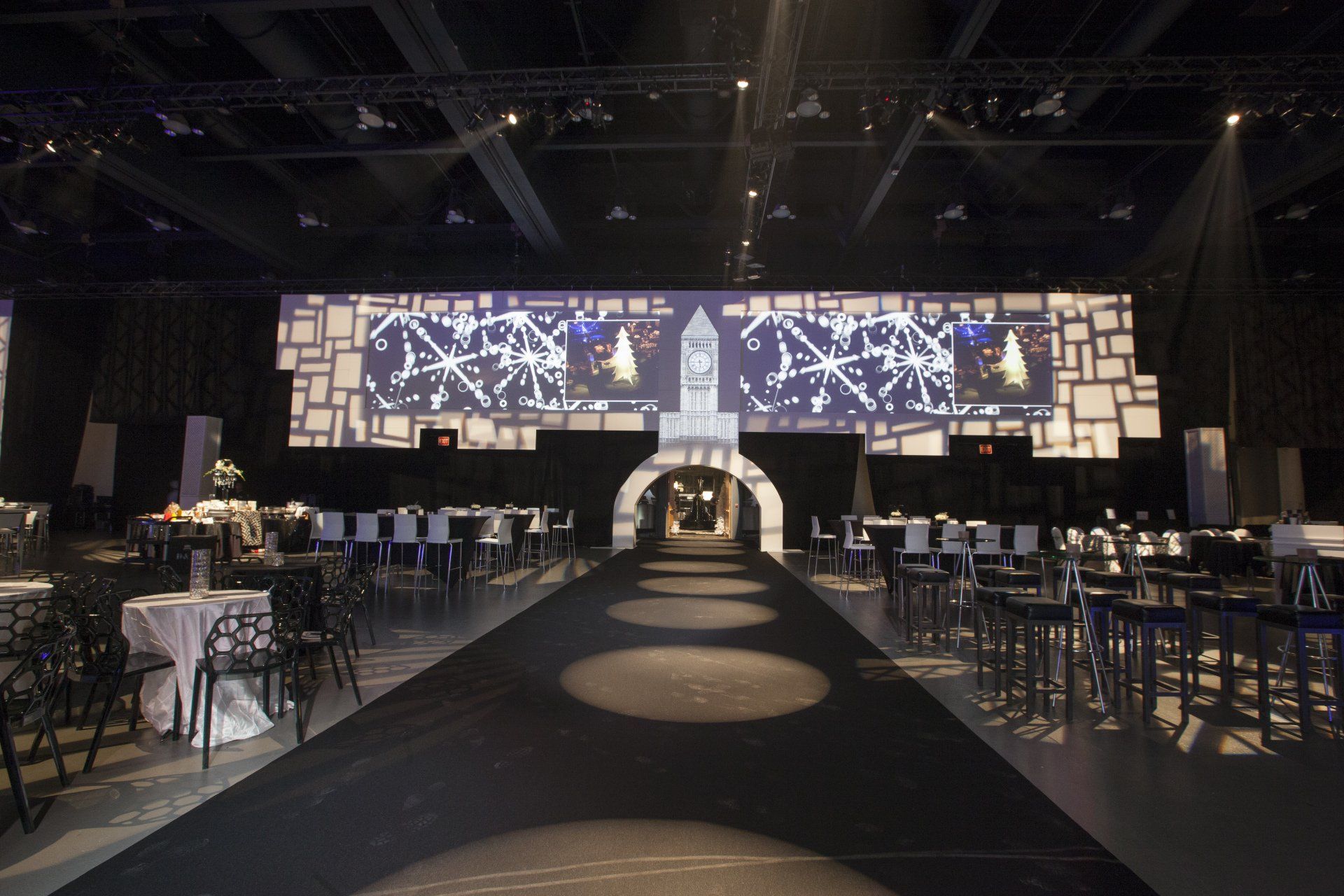 A large room with tables and chairs and a large screen on the wall