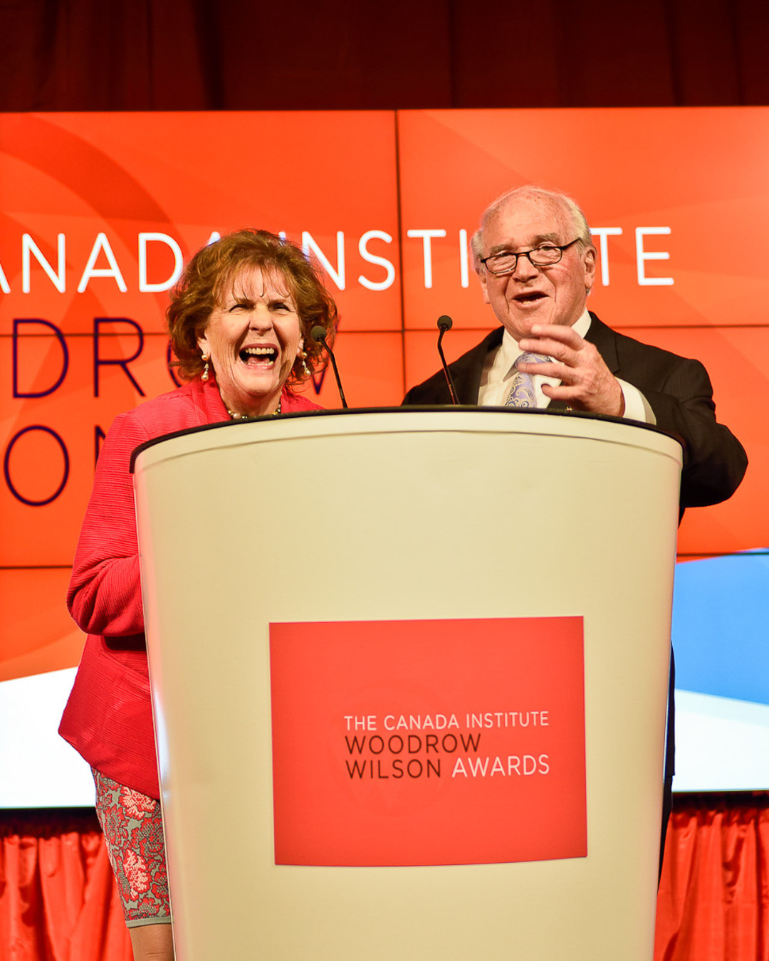 A man and woman are standing behind a podium that says woodrow wilson awards