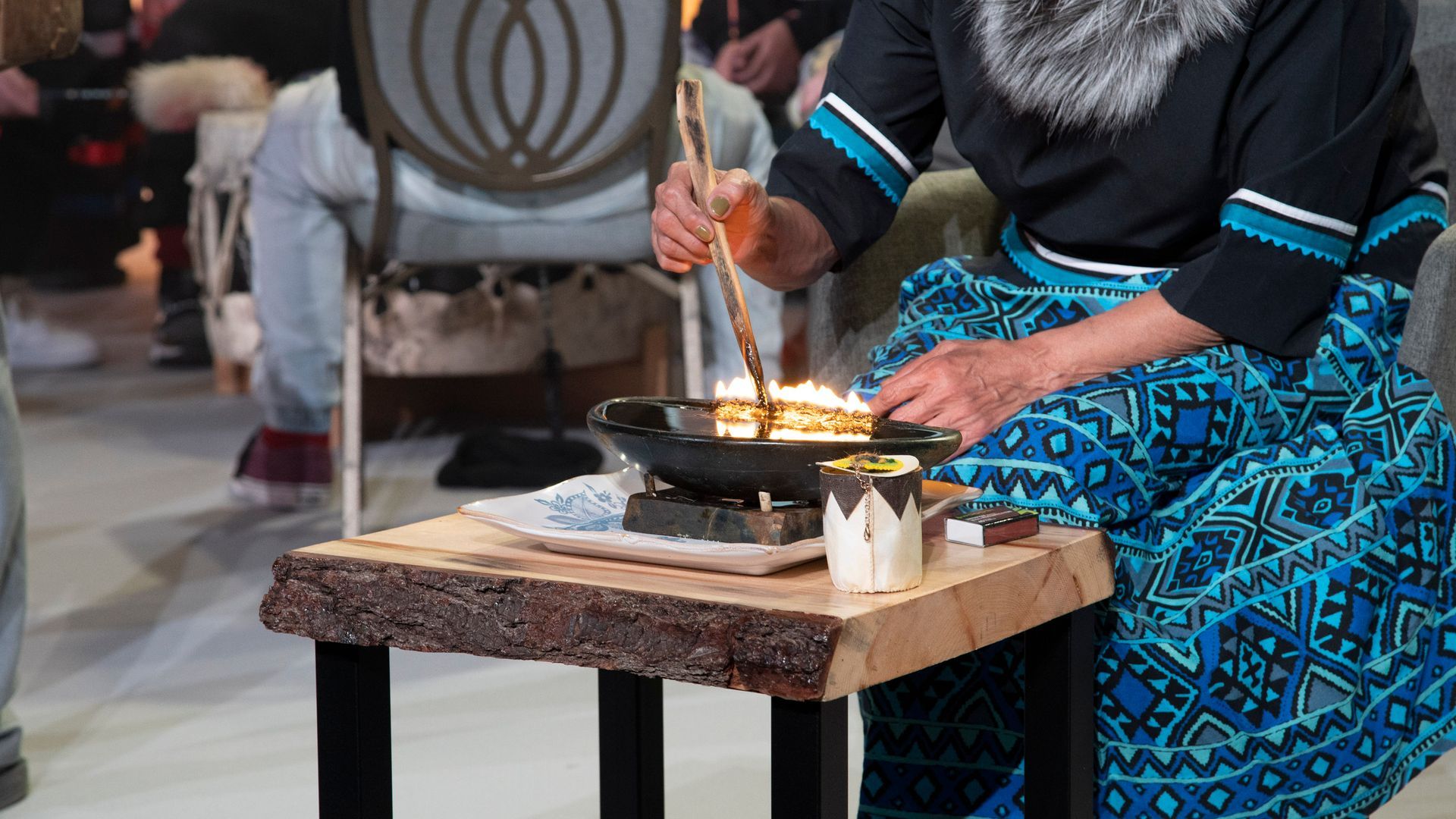 A man is sitting at a table cooking food in a pan.