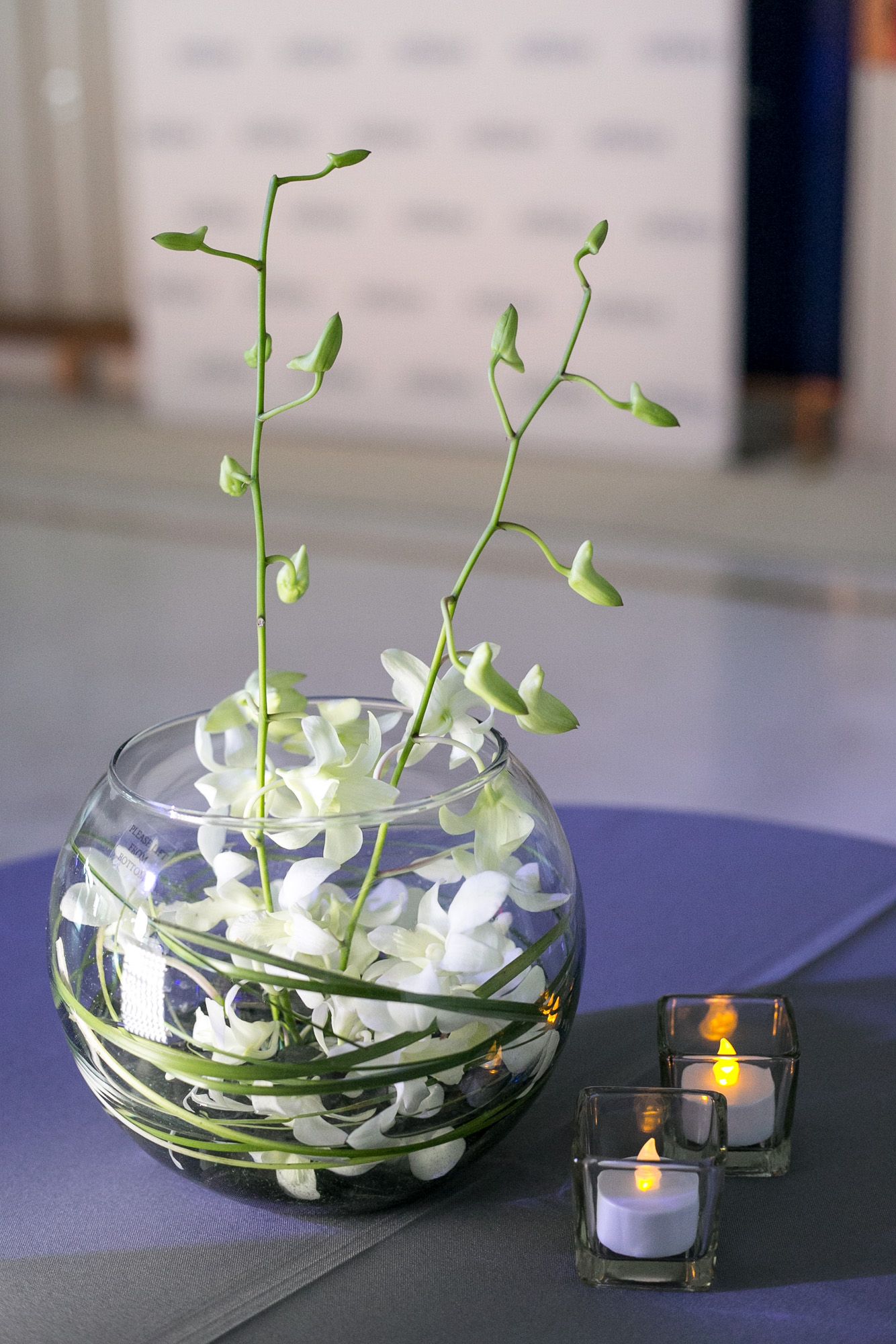 A vase filled with white flowers and candles on a table