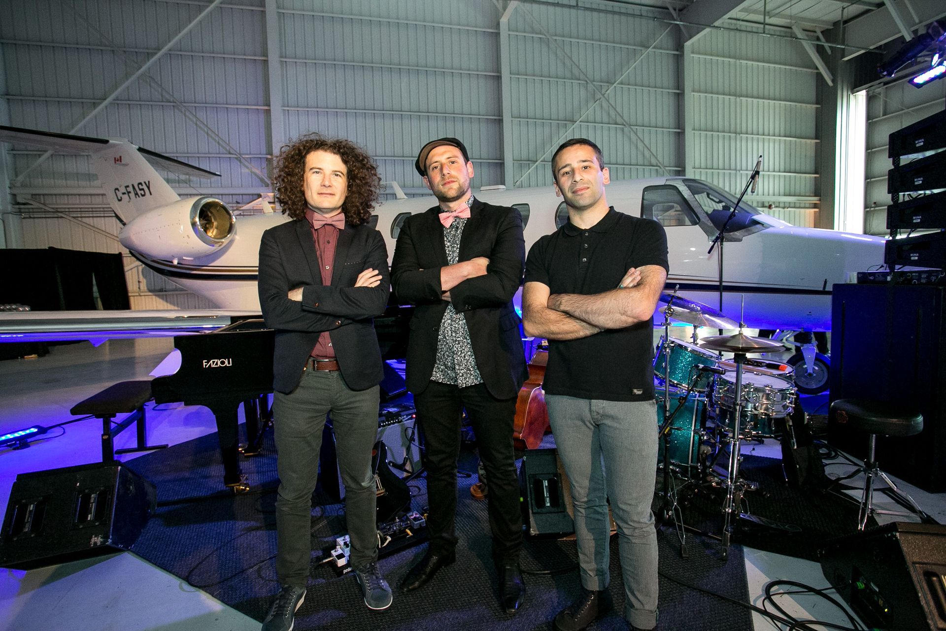 Three men are standing in front of a plane in a hangar.