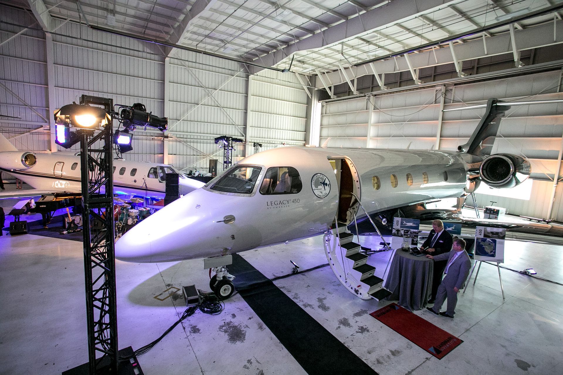 A small jet is parked in a hangar next to a table.