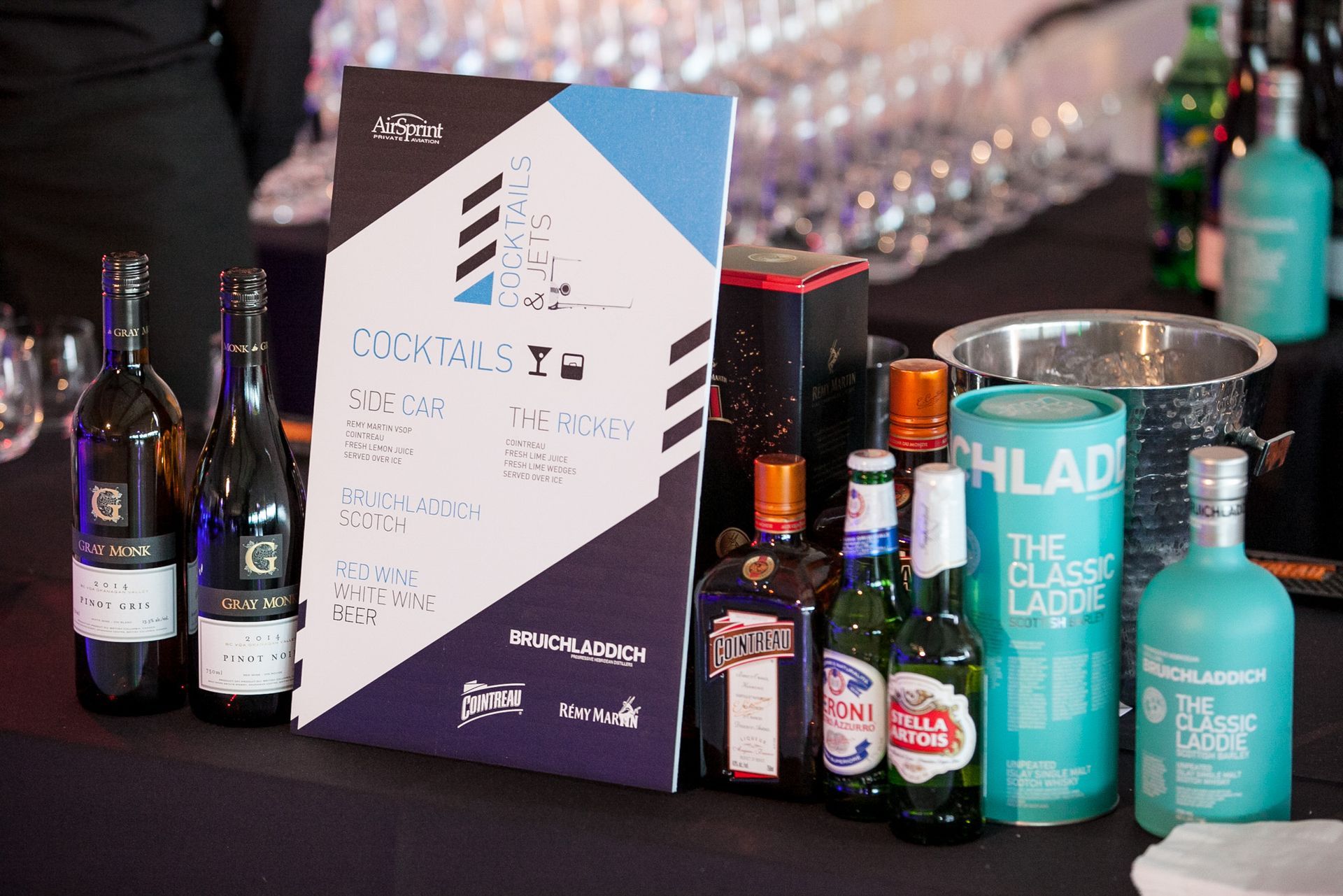 A table with bottles of alcohol and a sign on it.