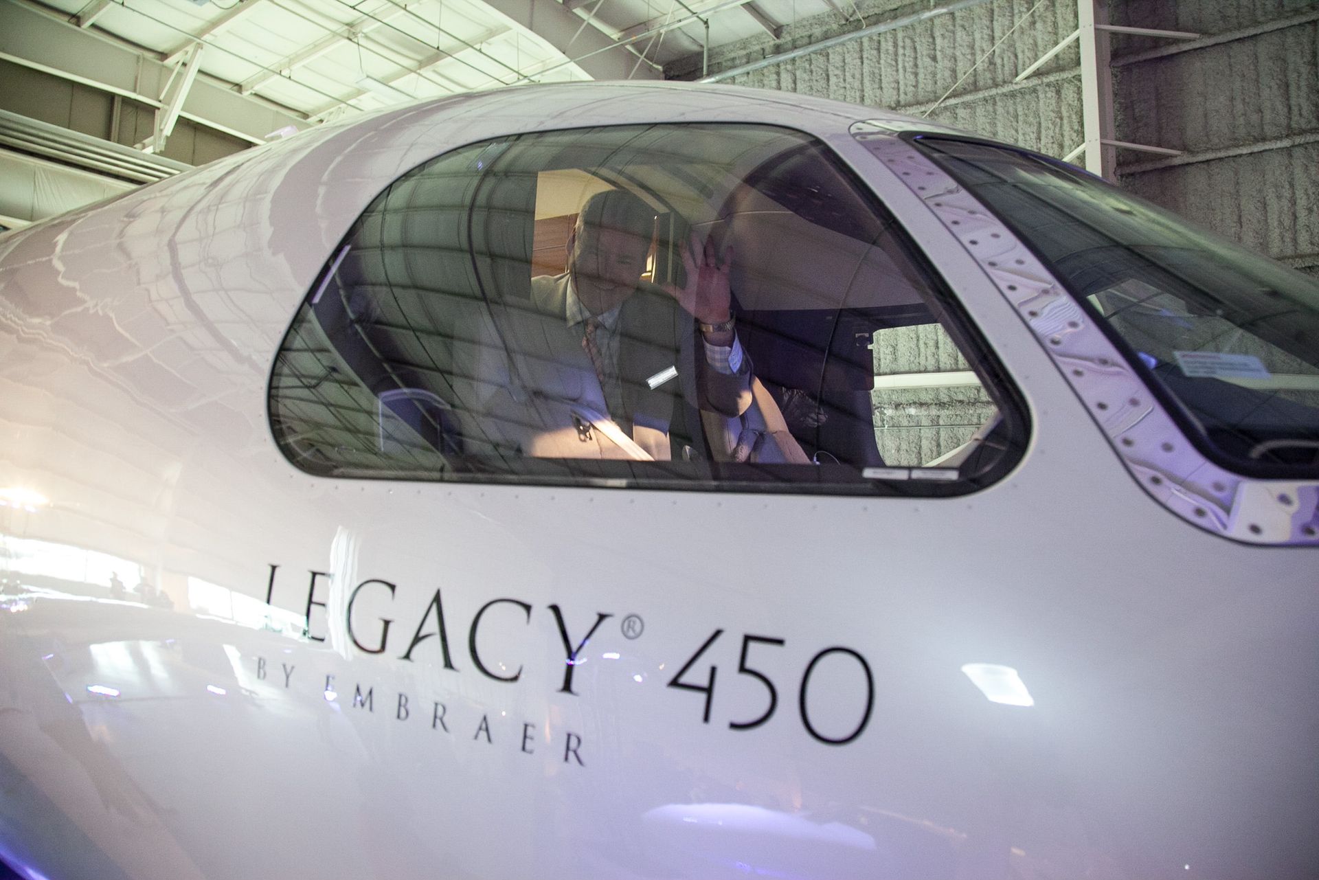 A man is sitting in the cockpit of a legacy 450 airplane.