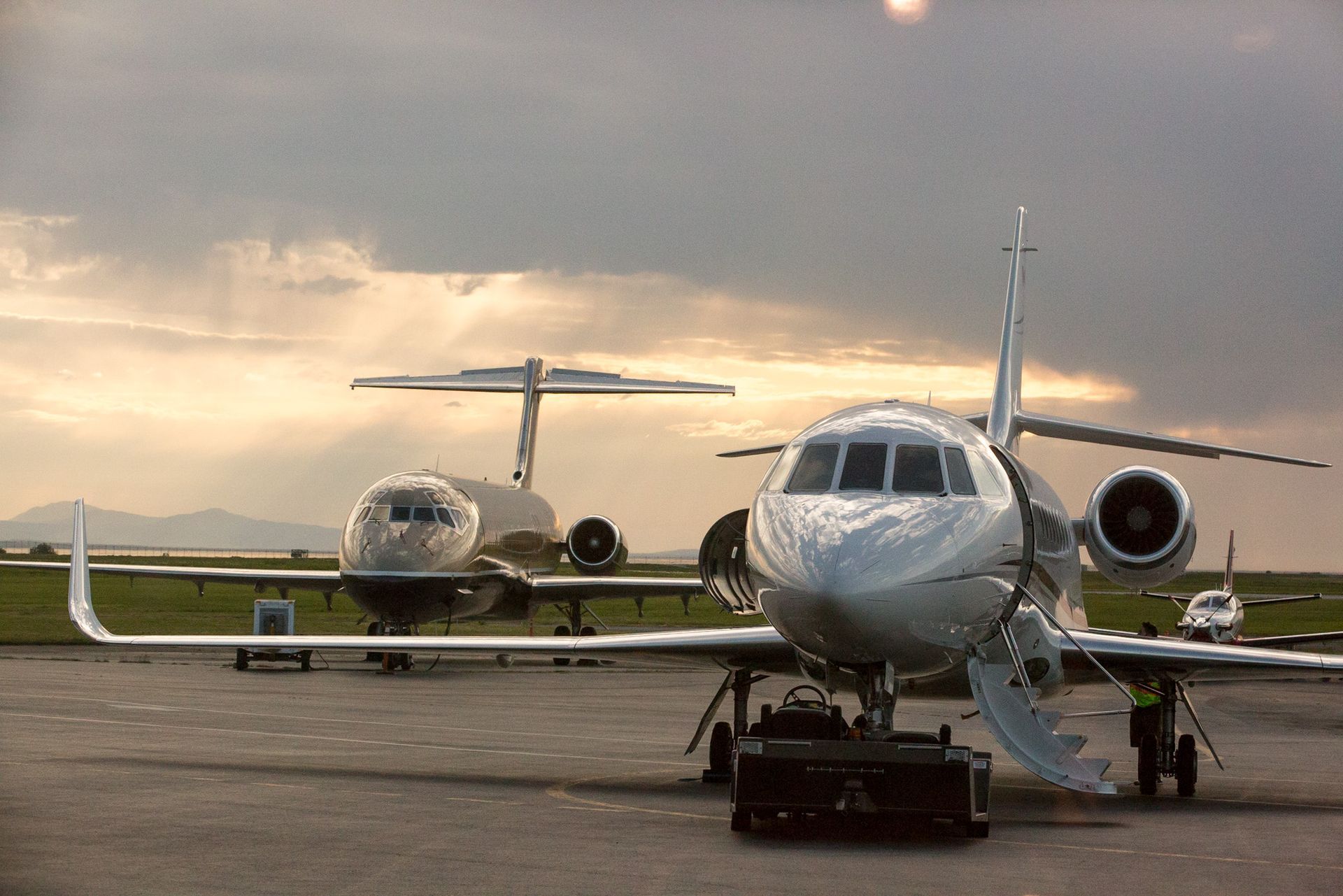 Two private jets are parked on the tarmac at an airport