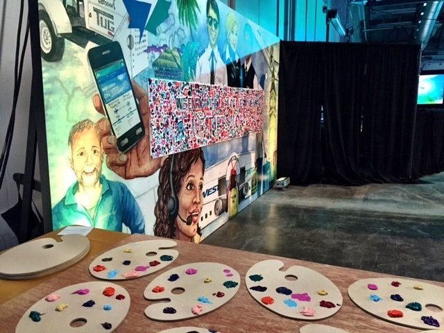 A table with painting palettes and a painting of a man holding a cell phone