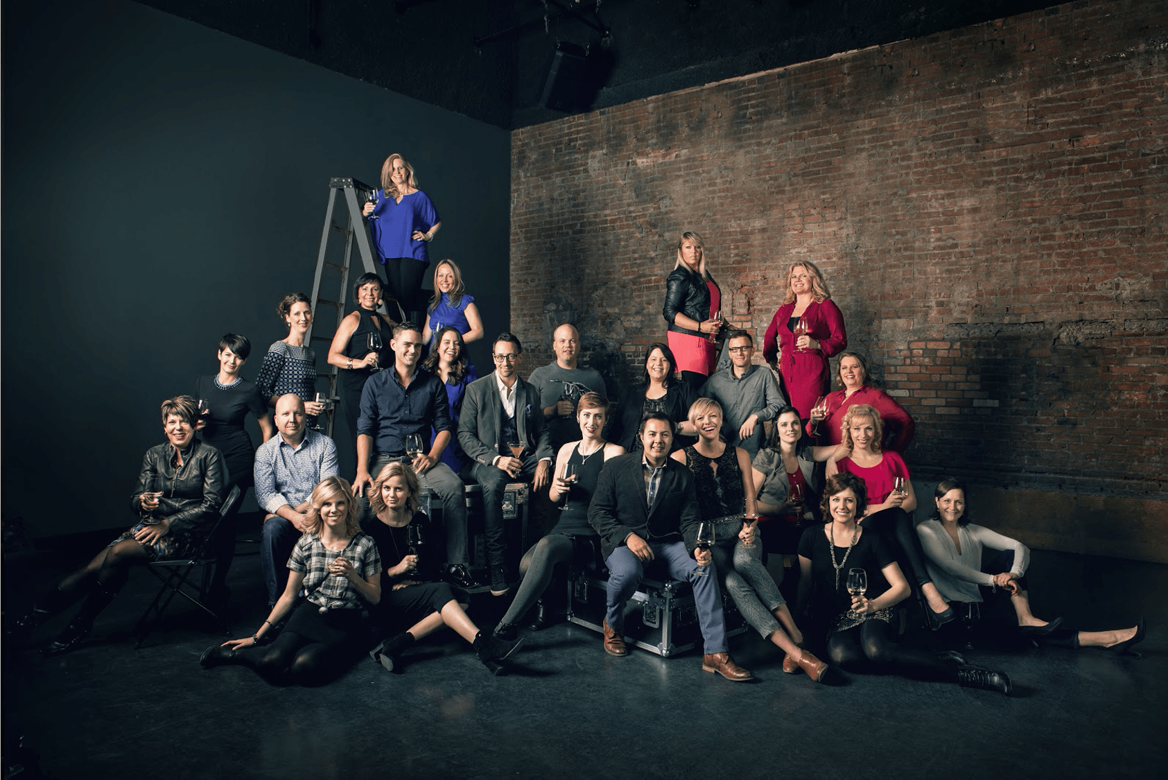 A large group of people are posing for a picture in front of a brick wall.