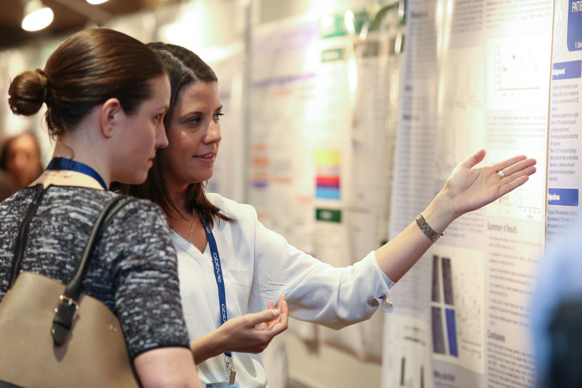 Two women are looking at a poster on a wall.