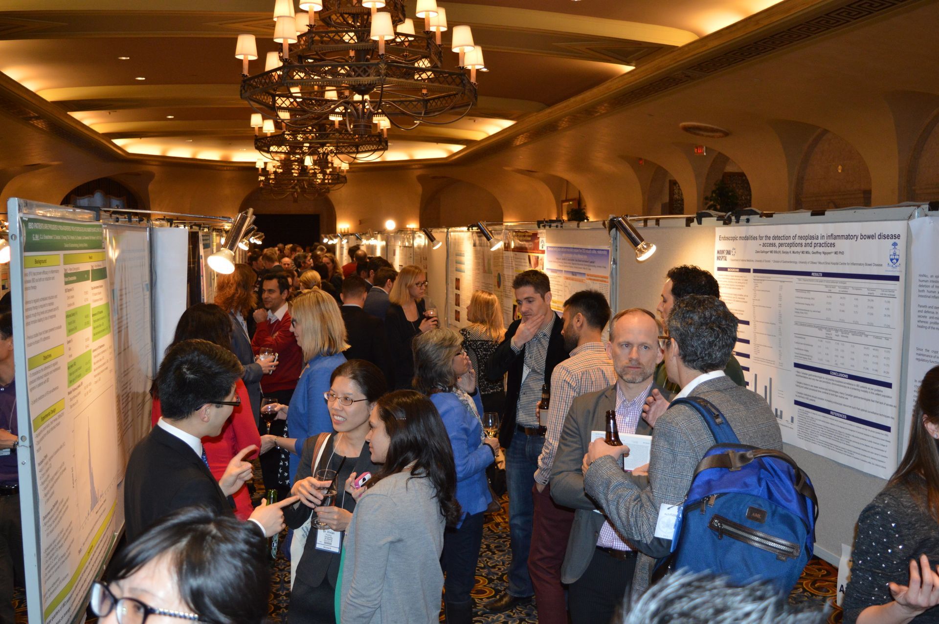 A large group of people are standing in a room with posters on the wall.