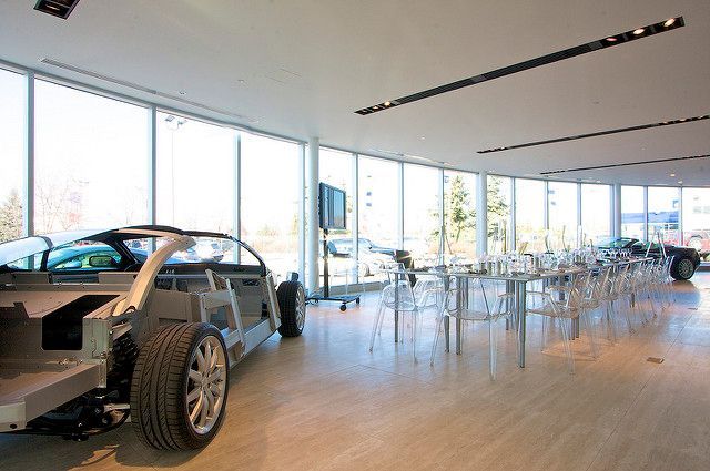 A car is sitting in a room with tables and chairs.