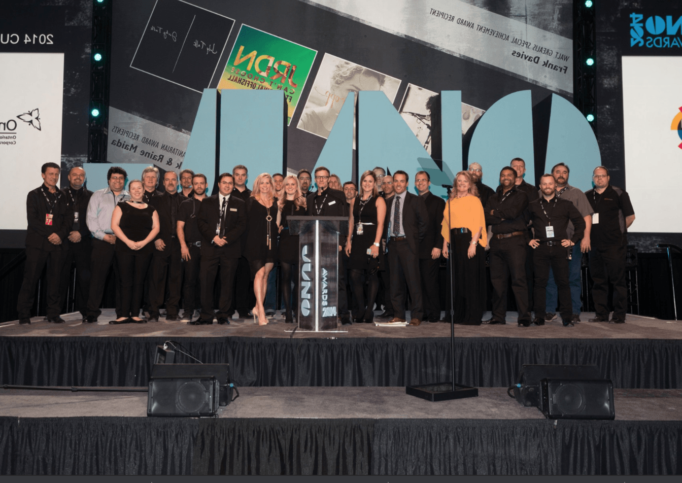 A group of people are standing on a stage in front of a large sign that says ' a ' on it