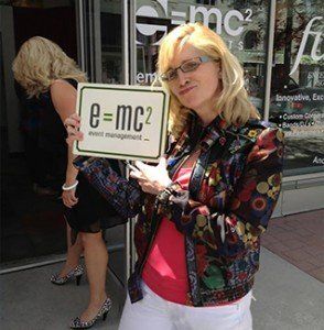 A woman holding a sign that says e = mc2