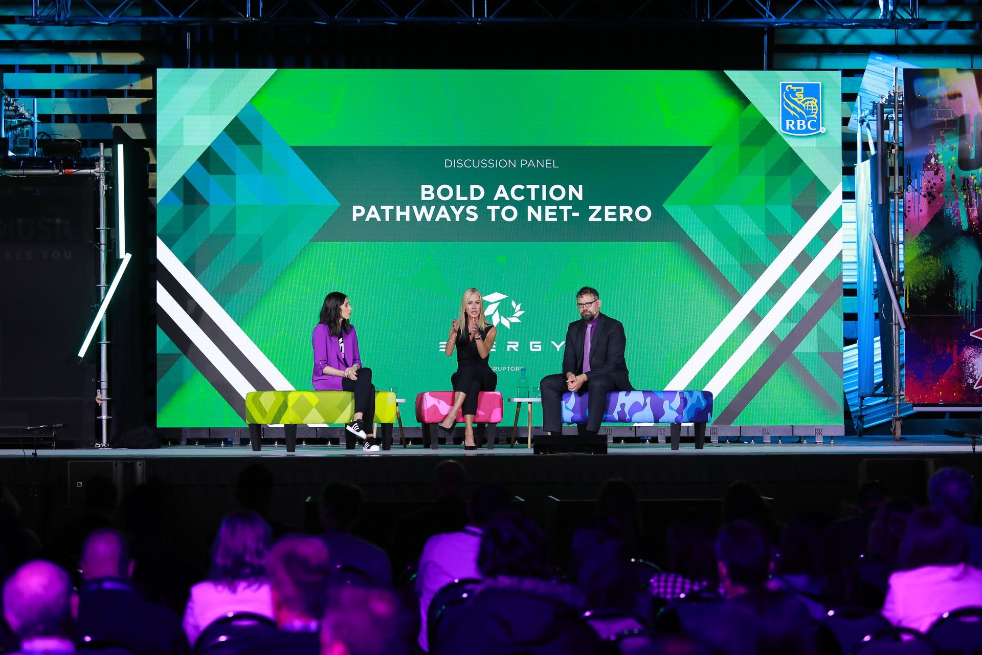 A group of people are sitting on a stage in front of a large screen.