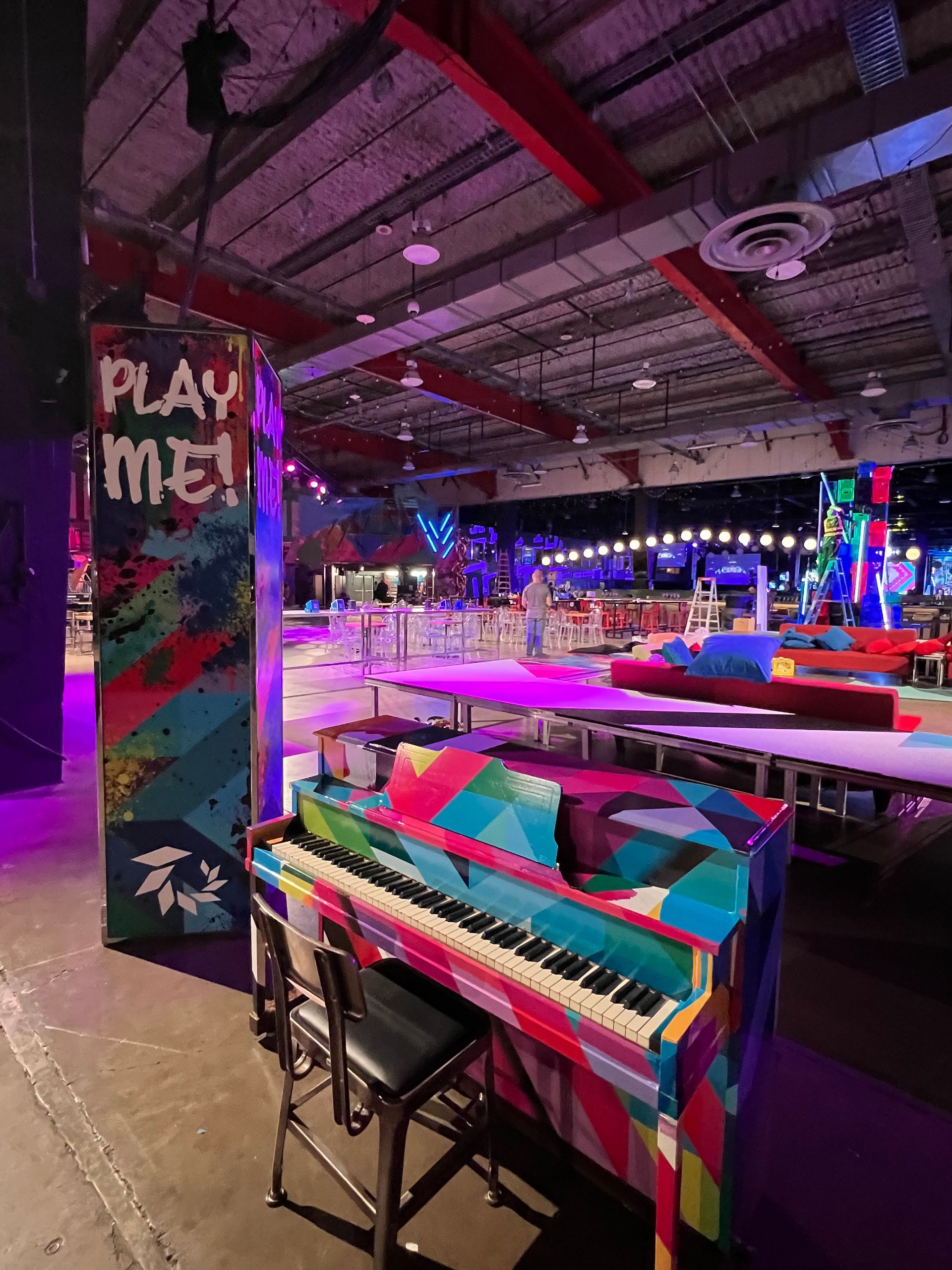 A colorful piano is sitting in front of a sign that says play me.