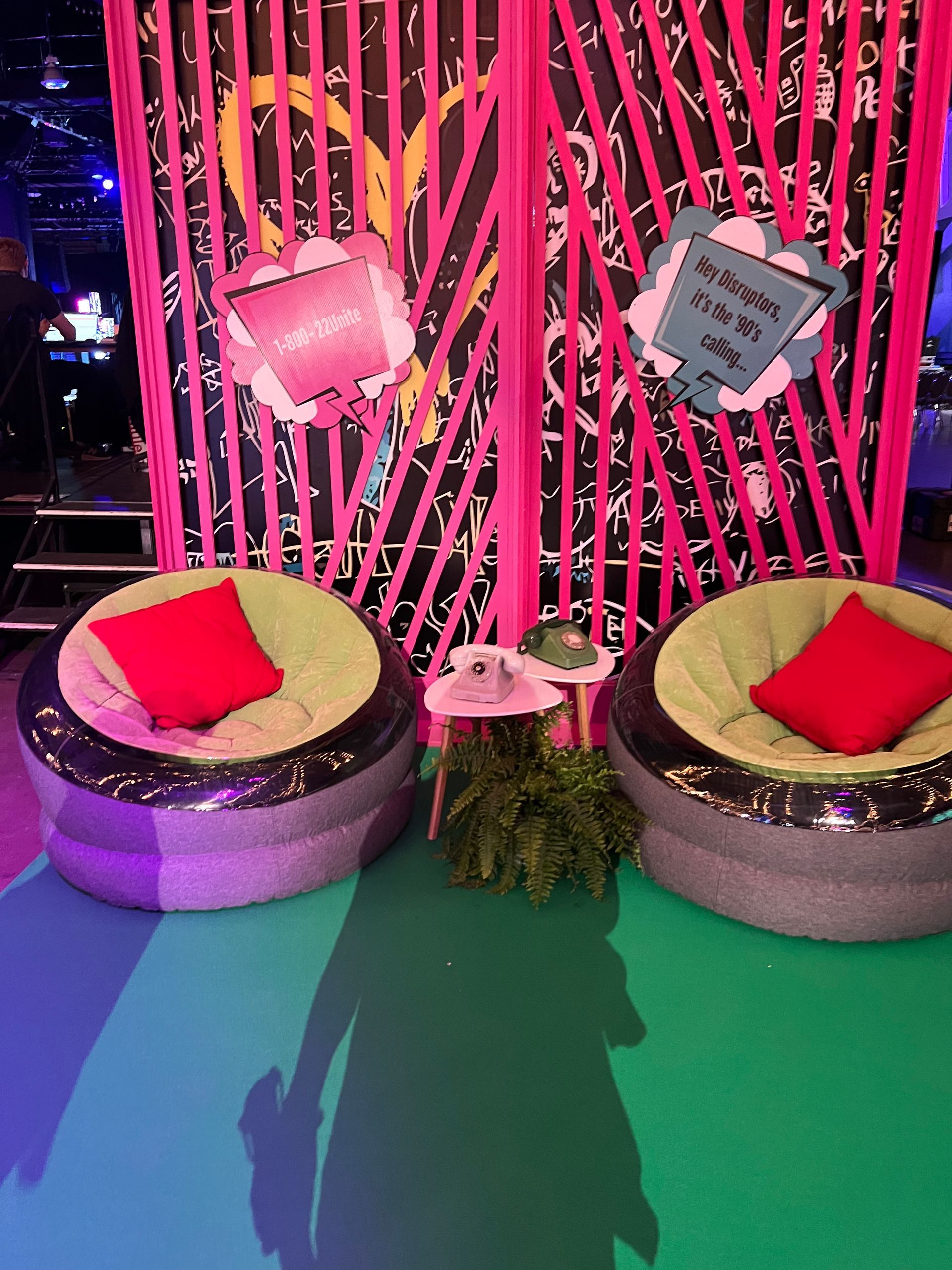 Two chairs with red pillows in front of a pink wall