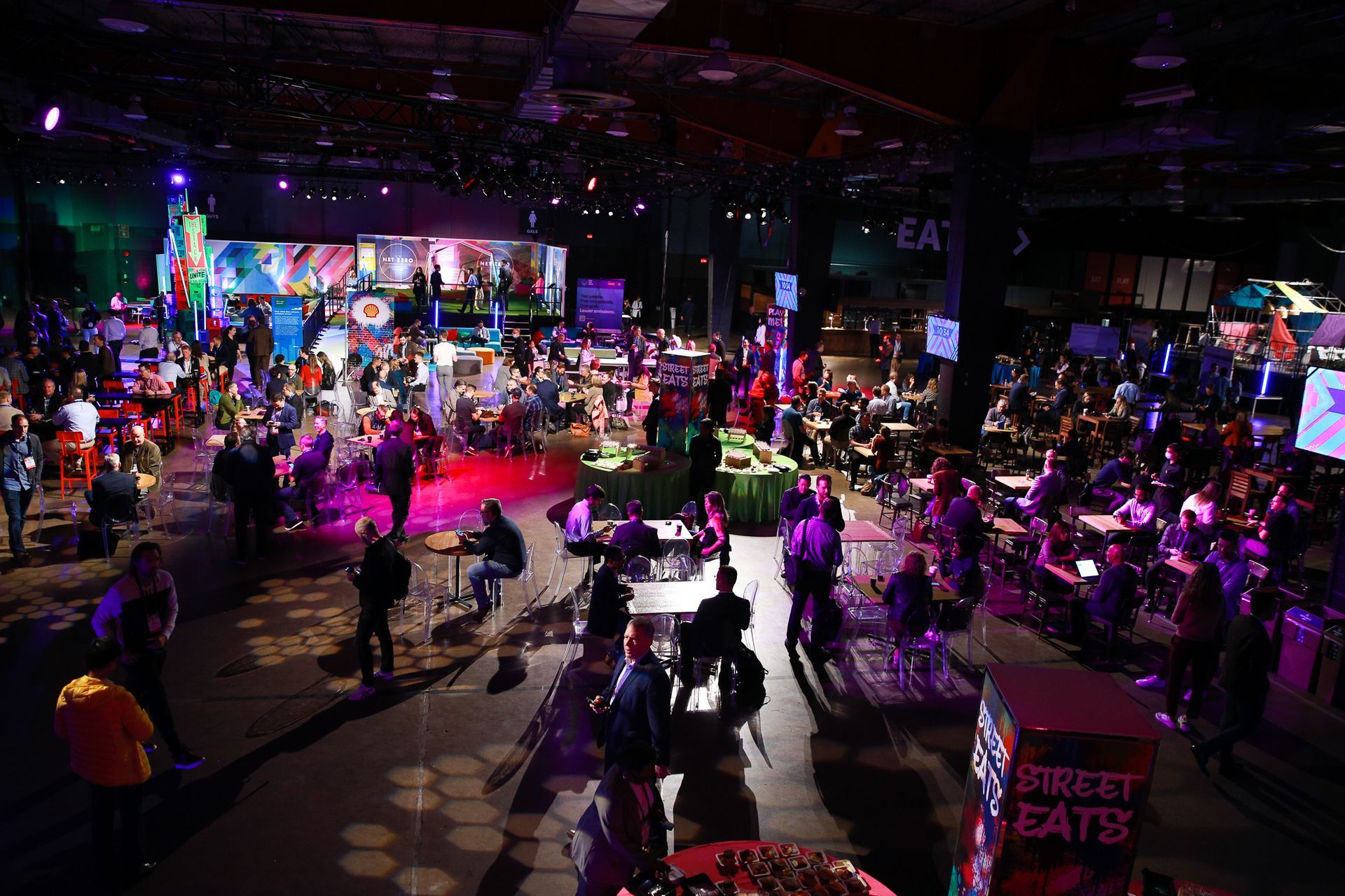 A large crowd of people are gathered in a large room with a sign that says direct cats.