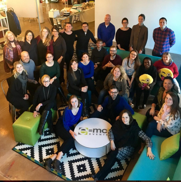 A group of people are posing for a picture in front of a table that says e = mc2