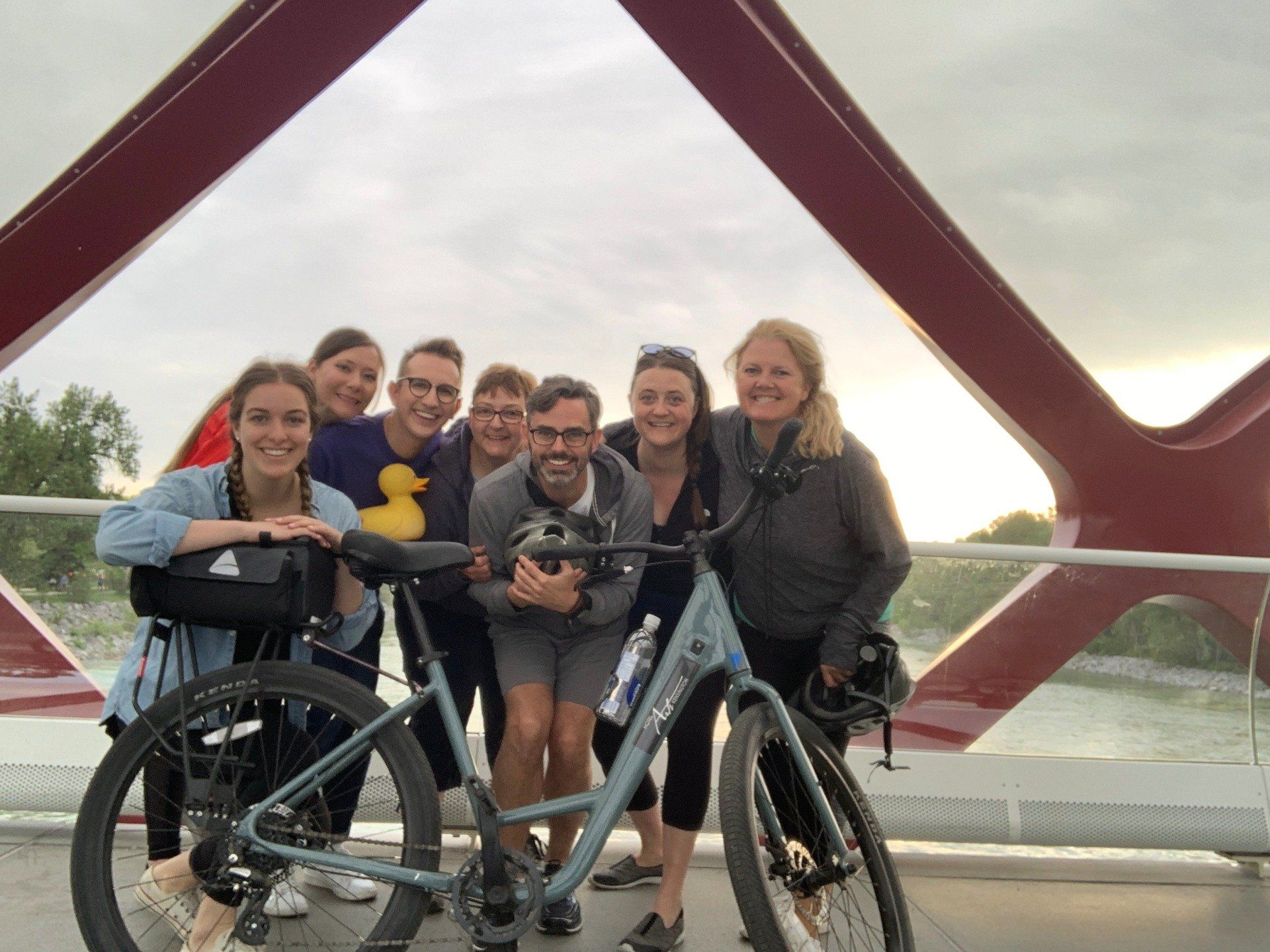 A group of people standing next to a bicycle on a bridge.