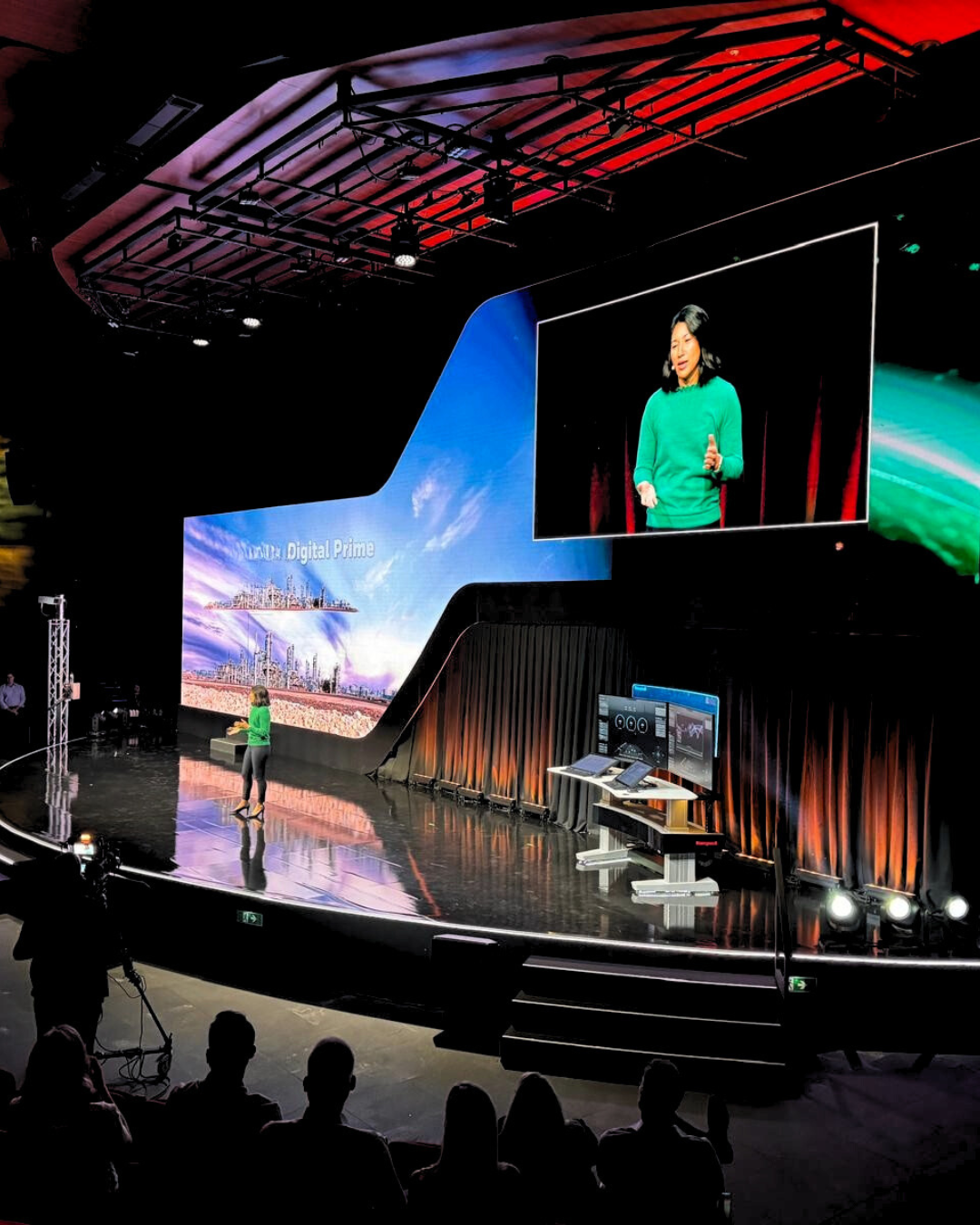 A woman in a green shirt is giving a speech on a stage
