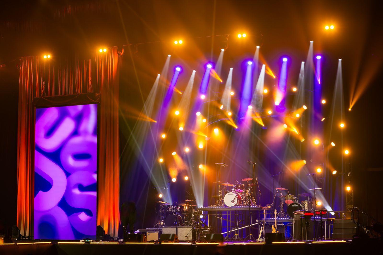 Two robot performers with lights dance at a party with people in white clothing.