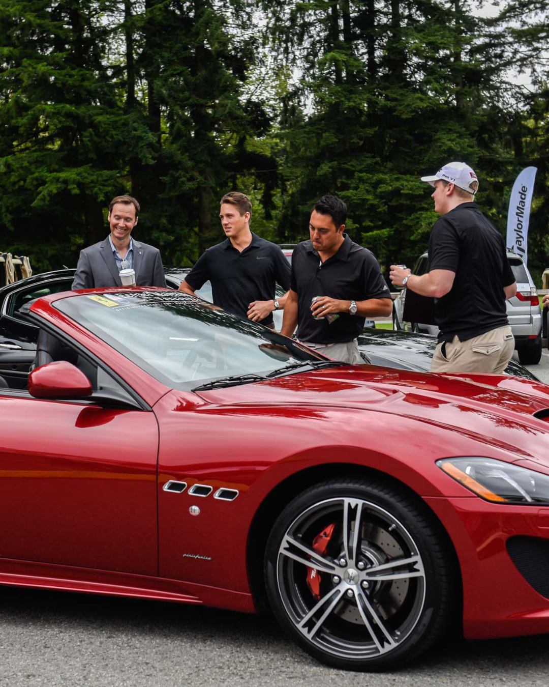 A group of men are standing around a red car that says ccc on the side