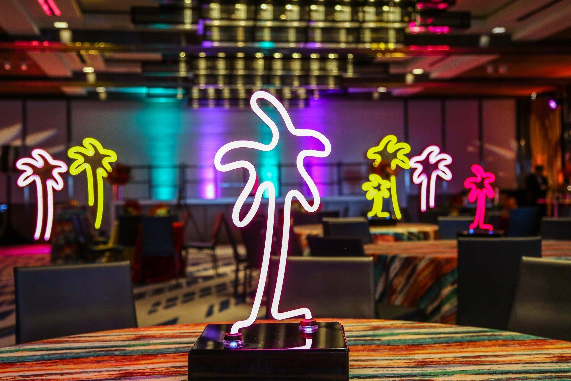 A neon sign of a palm tree is on a table in a room.