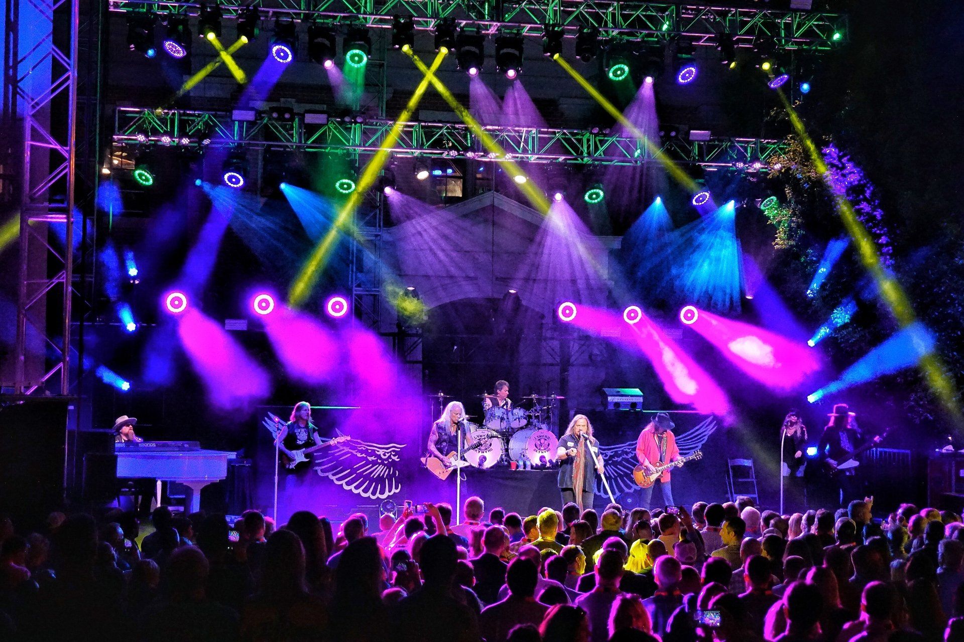 A group of people playing instruments on a stage with purple lights