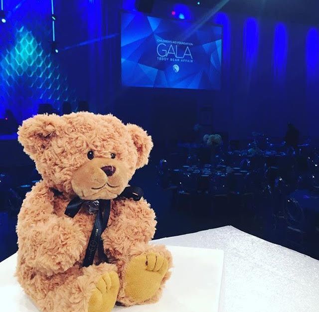 A teddy bear is sitting in front of a screen that says gala