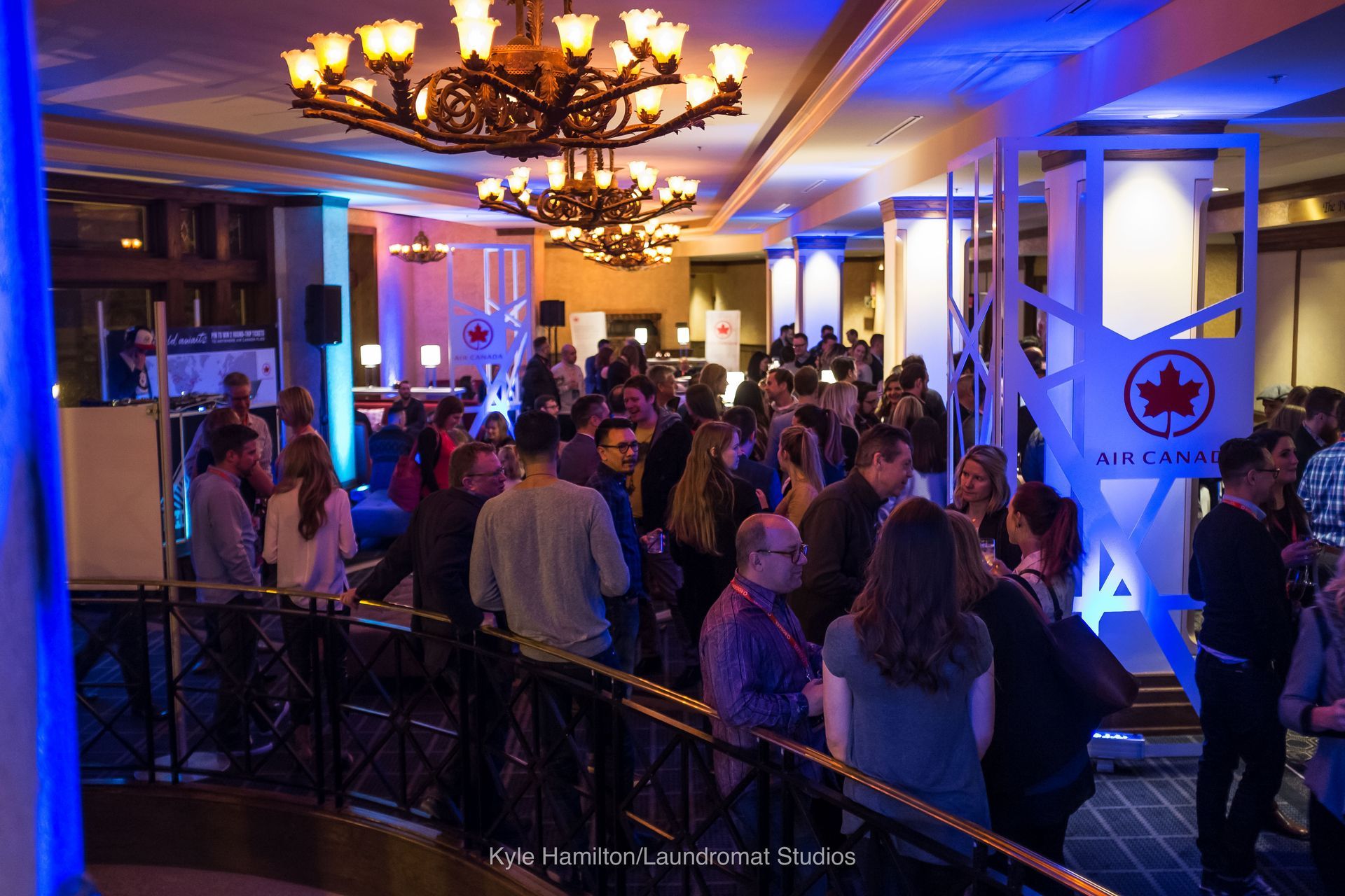 A large group of people are standing in a room with blue lights.