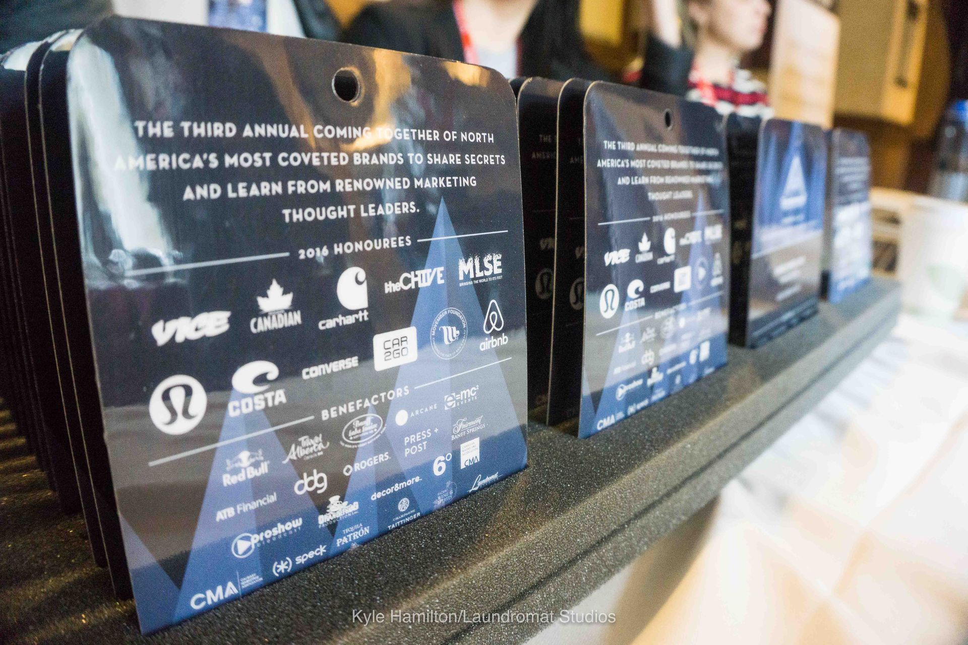 A row of name tags with logos on them are lined up on a table.