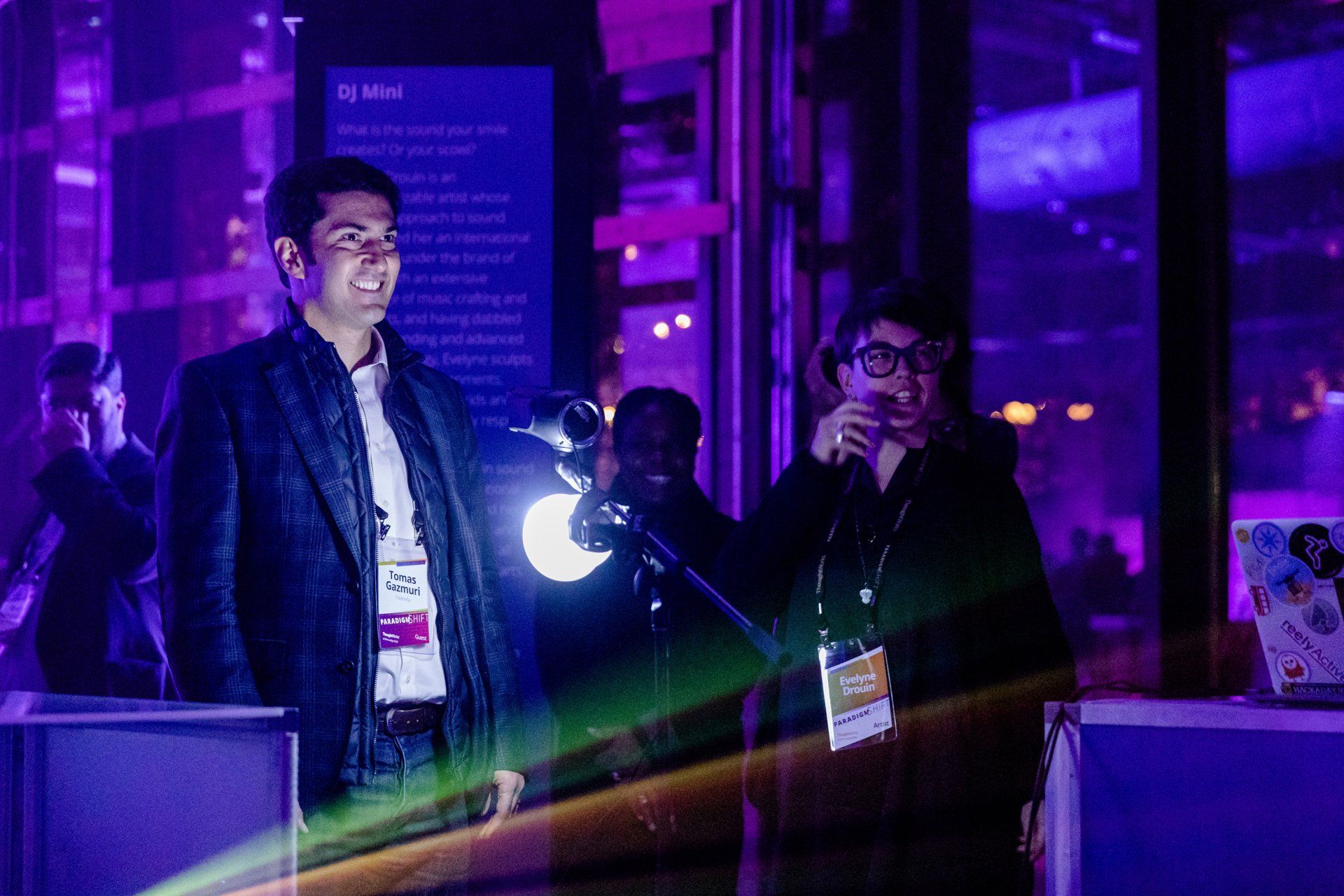A man is standing in front of a microphone in a dark room.