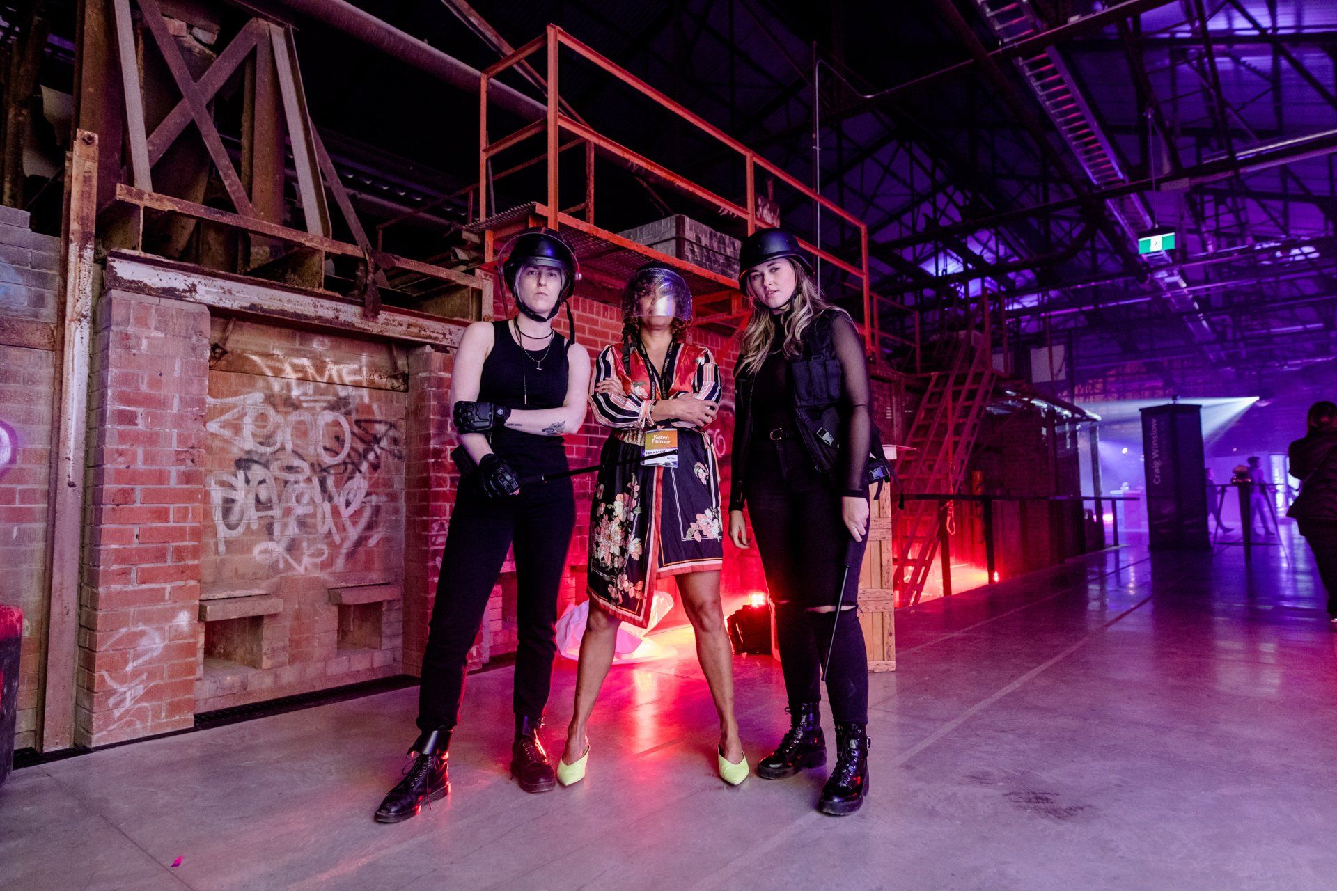 Three women are standing next to each other in a dark room.