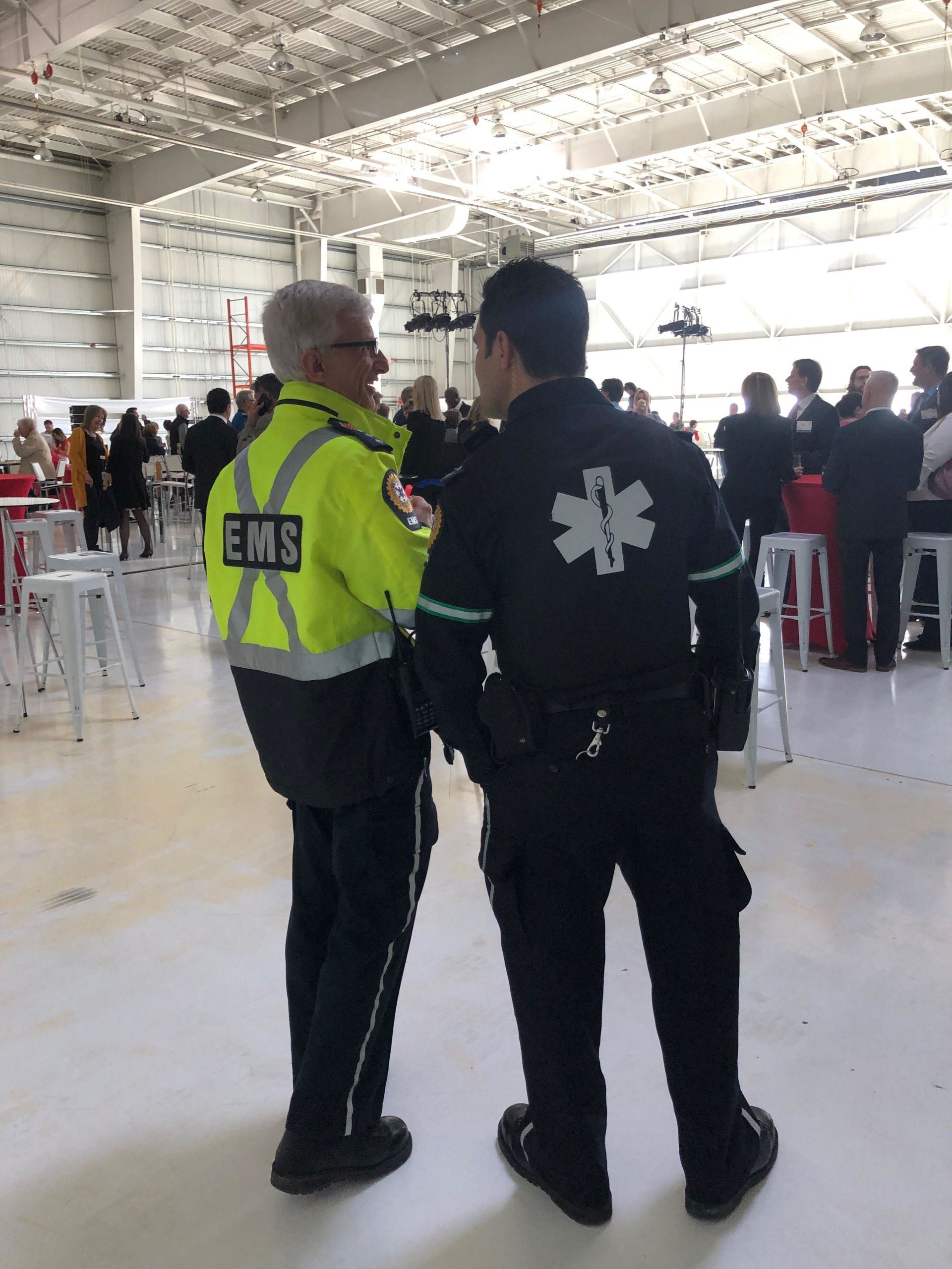 Two men in ems uniforms are standing next to each other